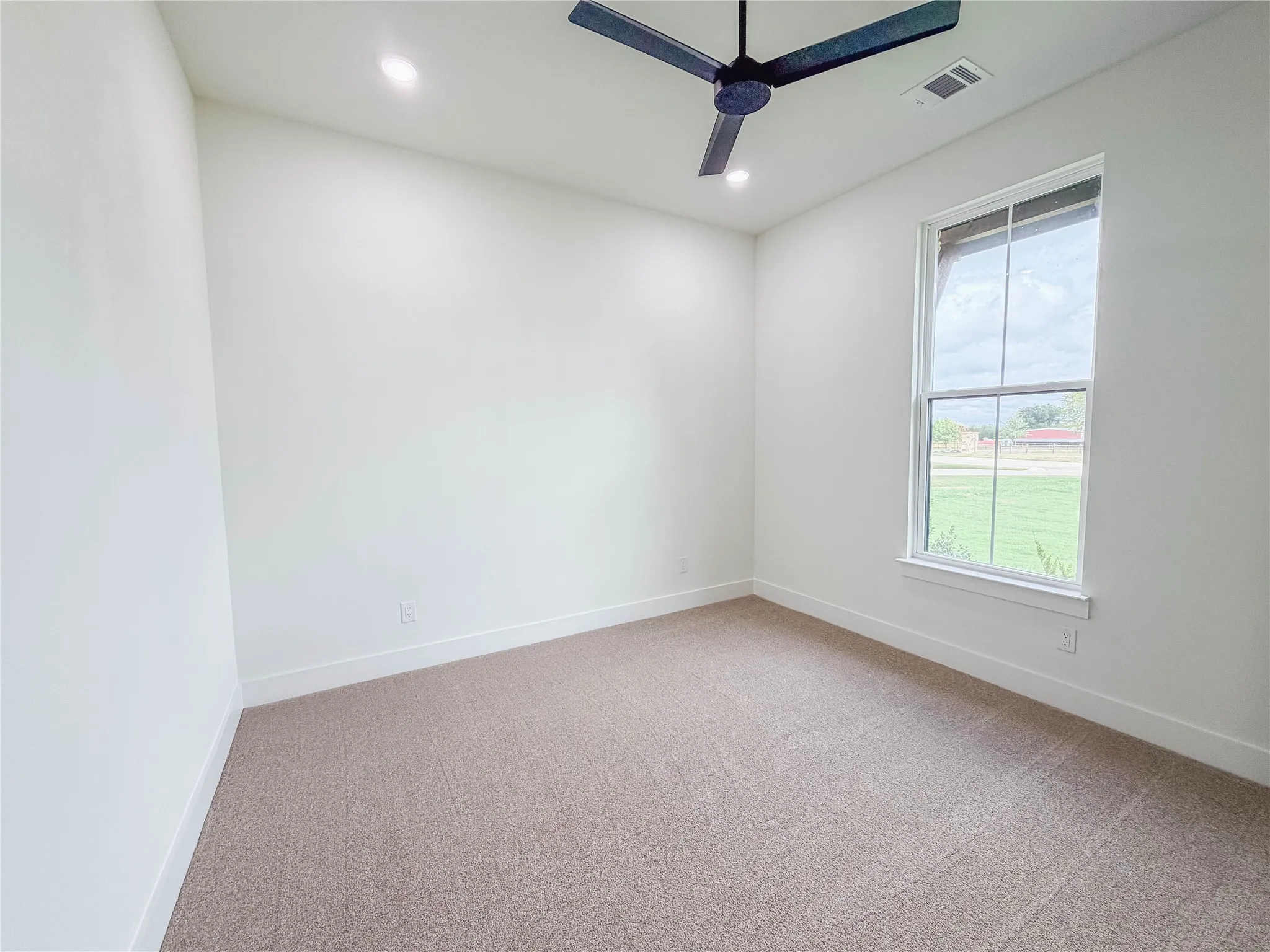 Neutral tone carpet flooring, white painted walls, recessed ceiling lighting, a modern black ceiling fan, and a double-pane window