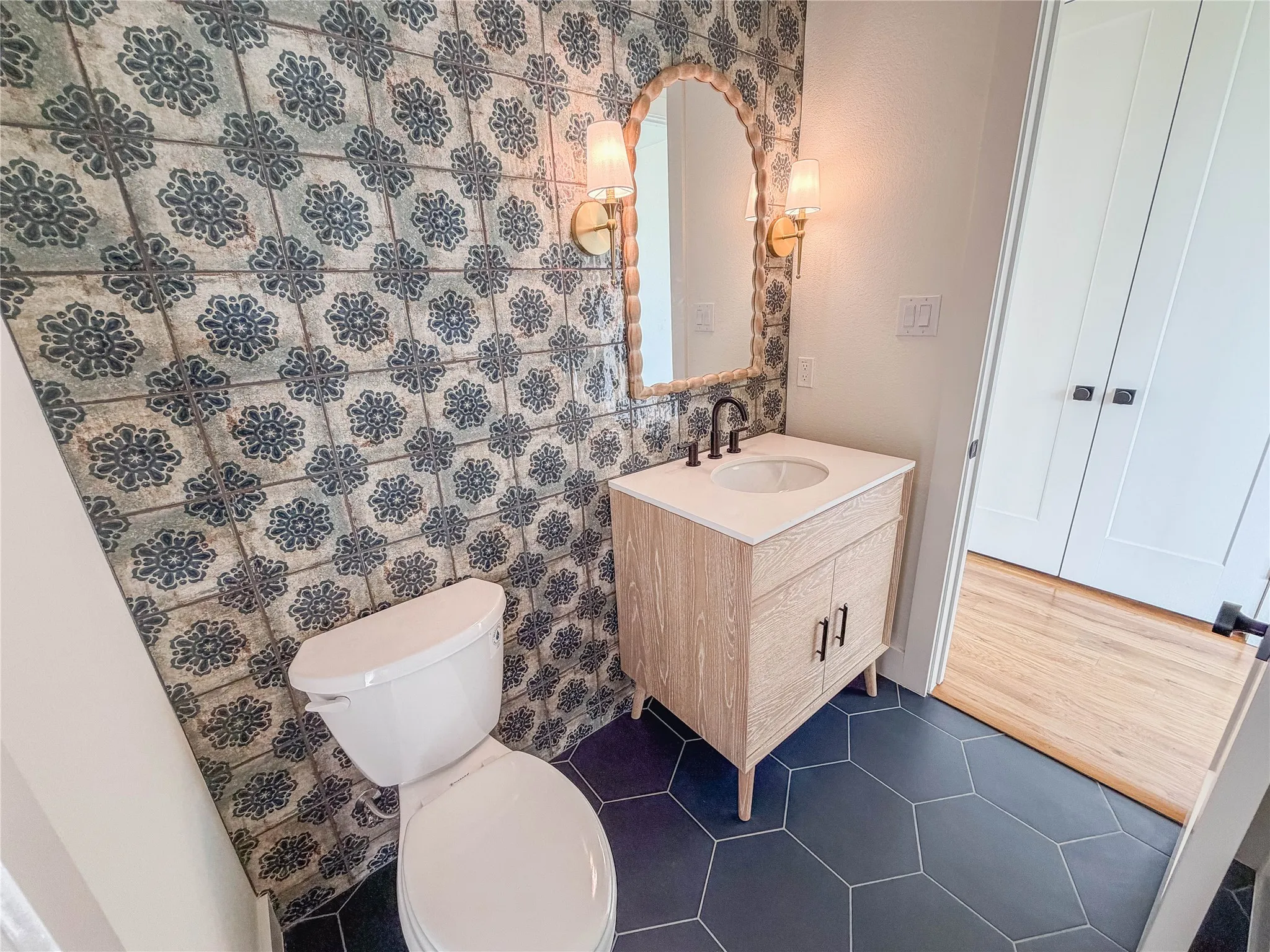 Powder room featuring a patterned accent wall, hexagon floor tiles, and a contemporary vanity with a wall-mounted mirror
