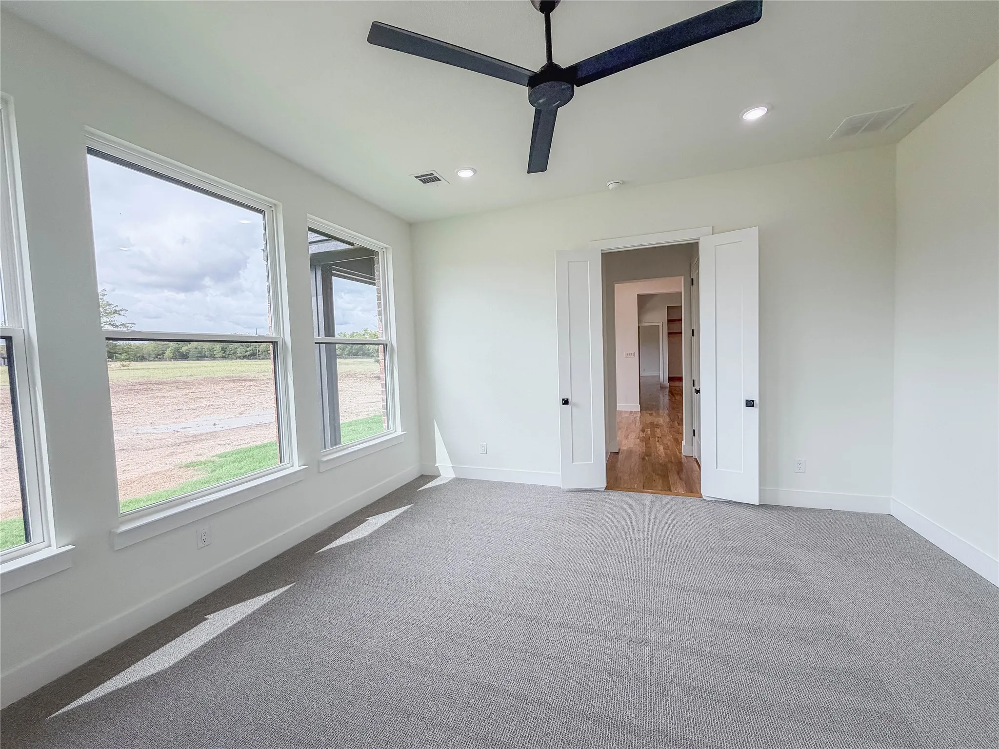 Wall-to-wall carpeting, dual entry doors, multiple windows, recessed lighting, and a ceiling fan