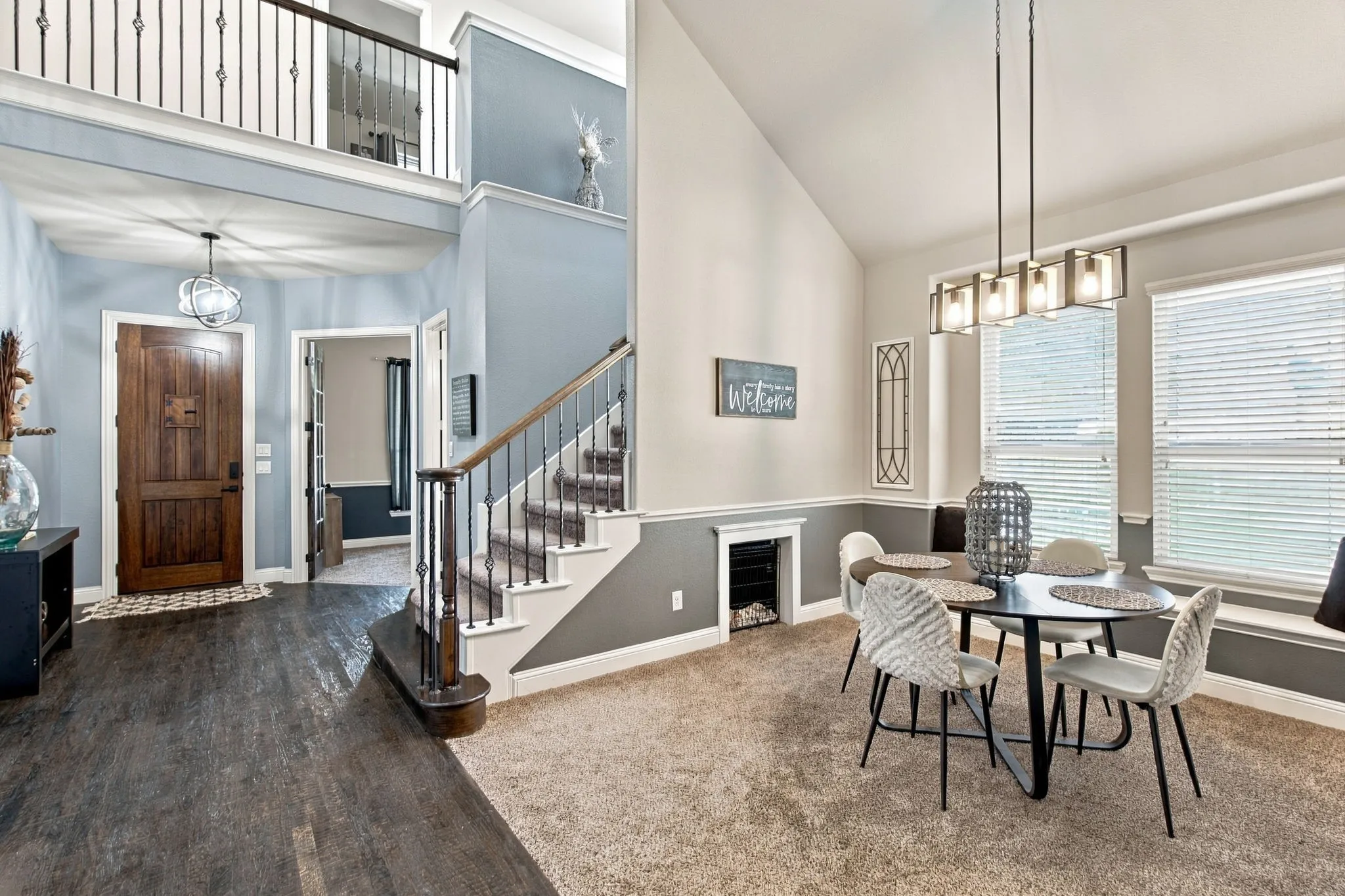 A beautiful view of the dining room and entryway highlights the staircase with decorative iron balusters, wood handrail, and distinctive architectural details.