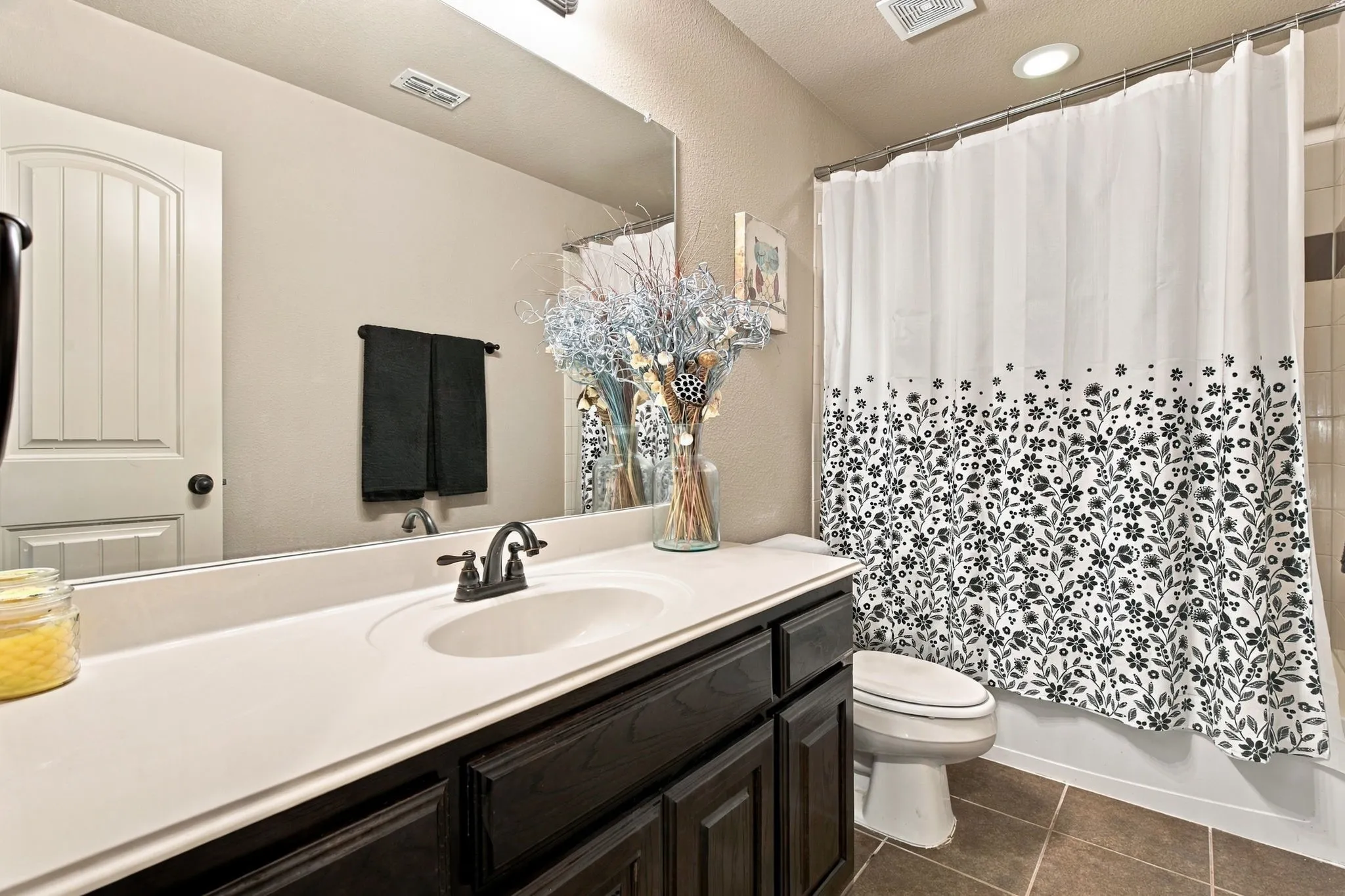 Additional upstairs bathroom with a tub-shower combination, dark wood cabinetry, spacious vanity countertop, and tile flooring.