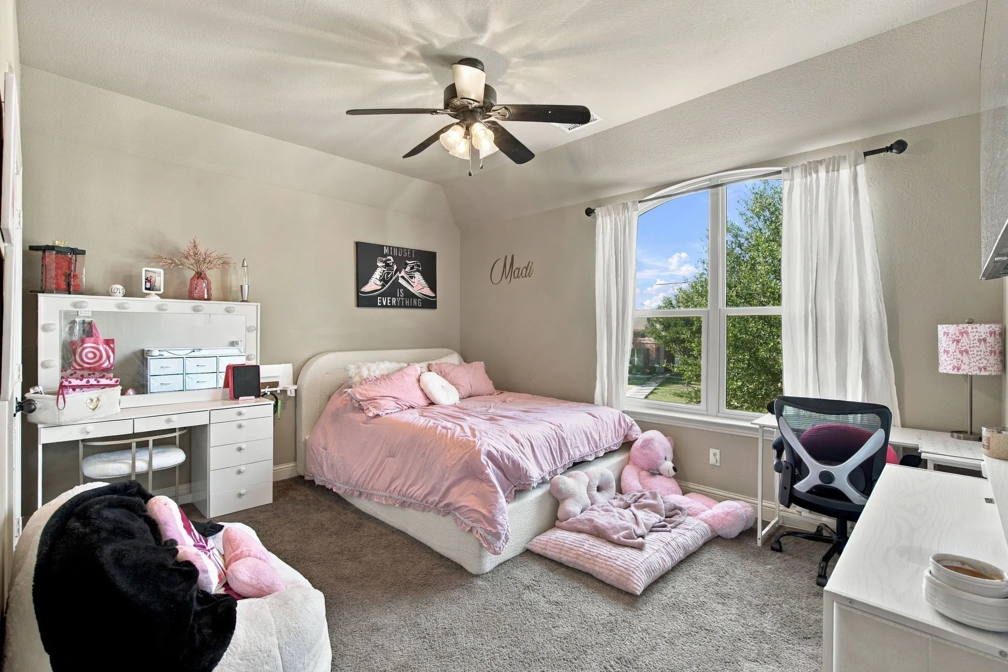 Bright upstairs bedroom with a large arched window, ceiling fan, and plenty of space for bedroom furniture, a desk, or a personal sitting area.
