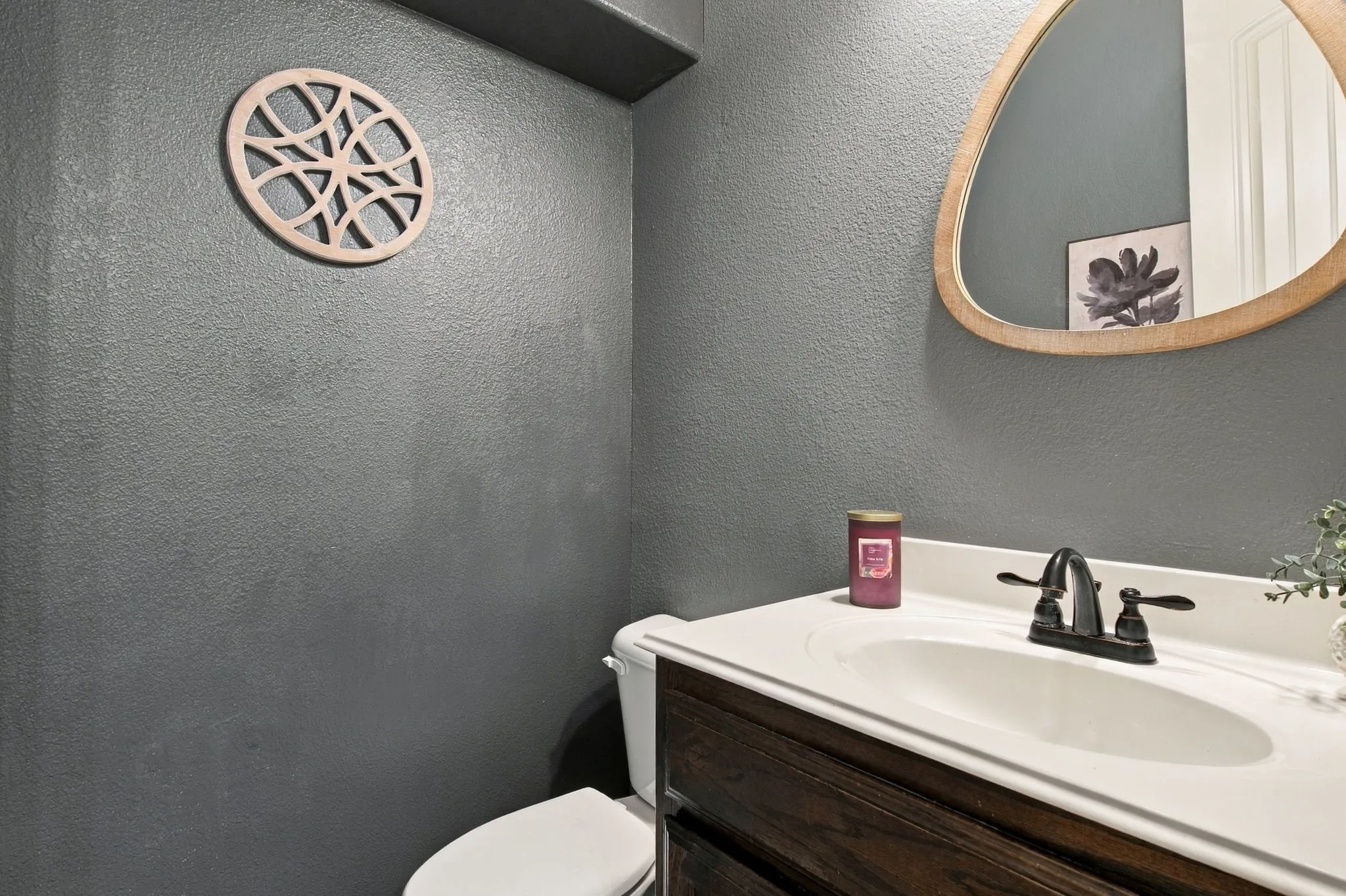 Convenient downstairs half bath featuring a dark wood vanity, white countertop, contrasting charcoal walls, and a decorative mirror.