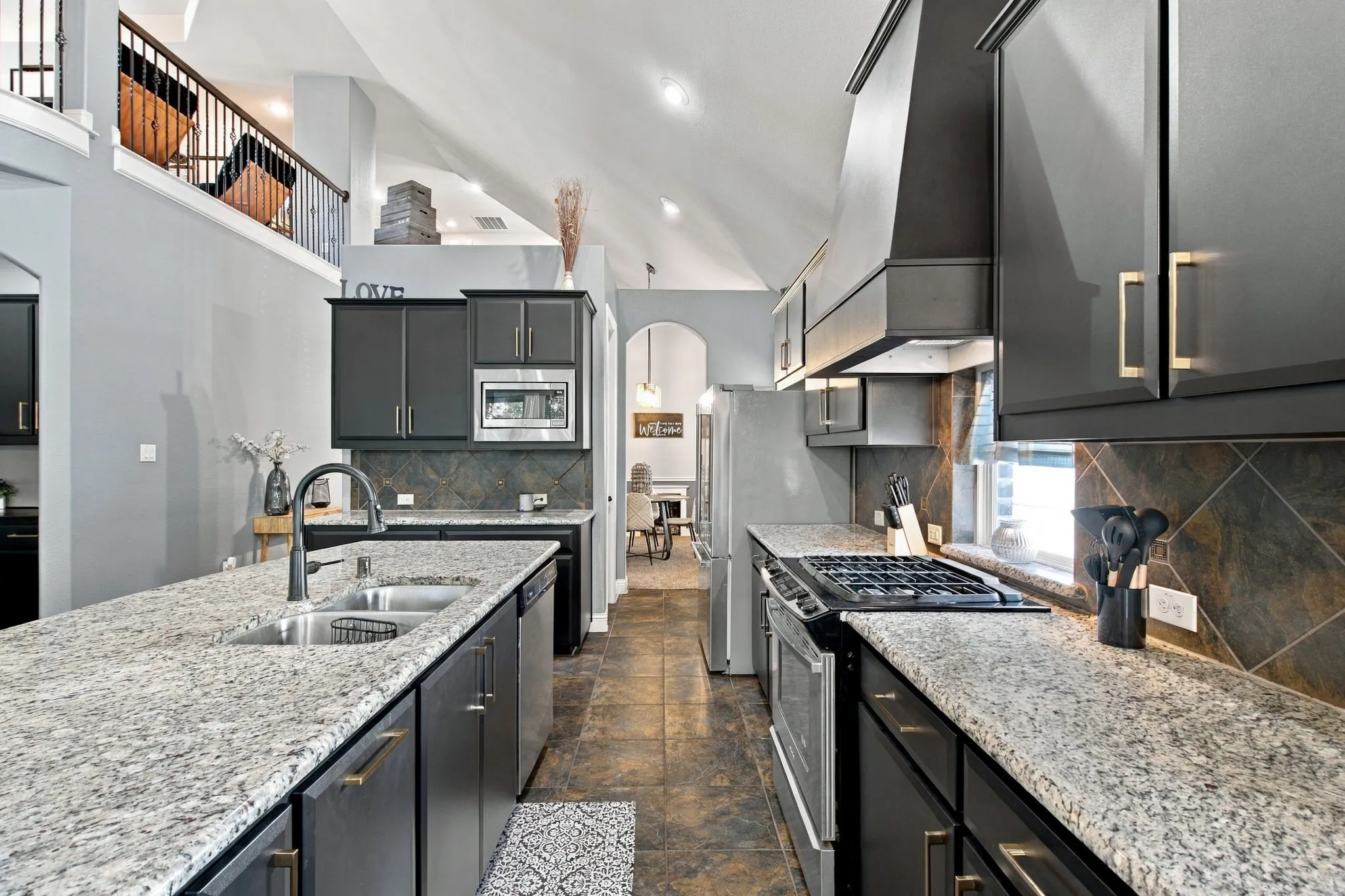 Generous counter space, a gas cooktop, stainless steel appliances, and a large island with a double-basin sink make this kitchen both practical and inviting.