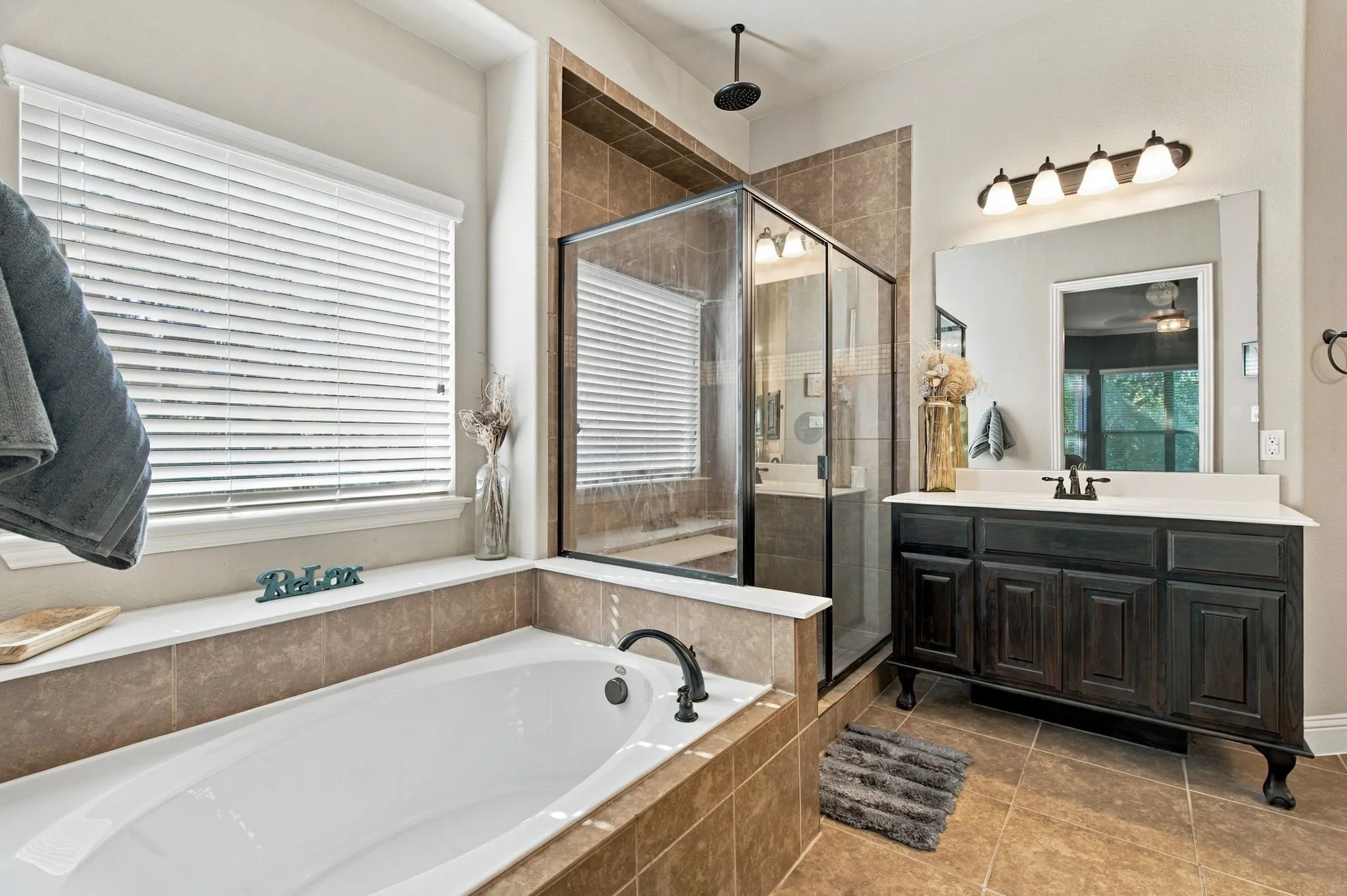 A closer look at the primary bathroom's separate soaking tub and glass-enclosed shower, featuring decorative tile accents, a rainfall-style showerhead, and a built-in shower bench.