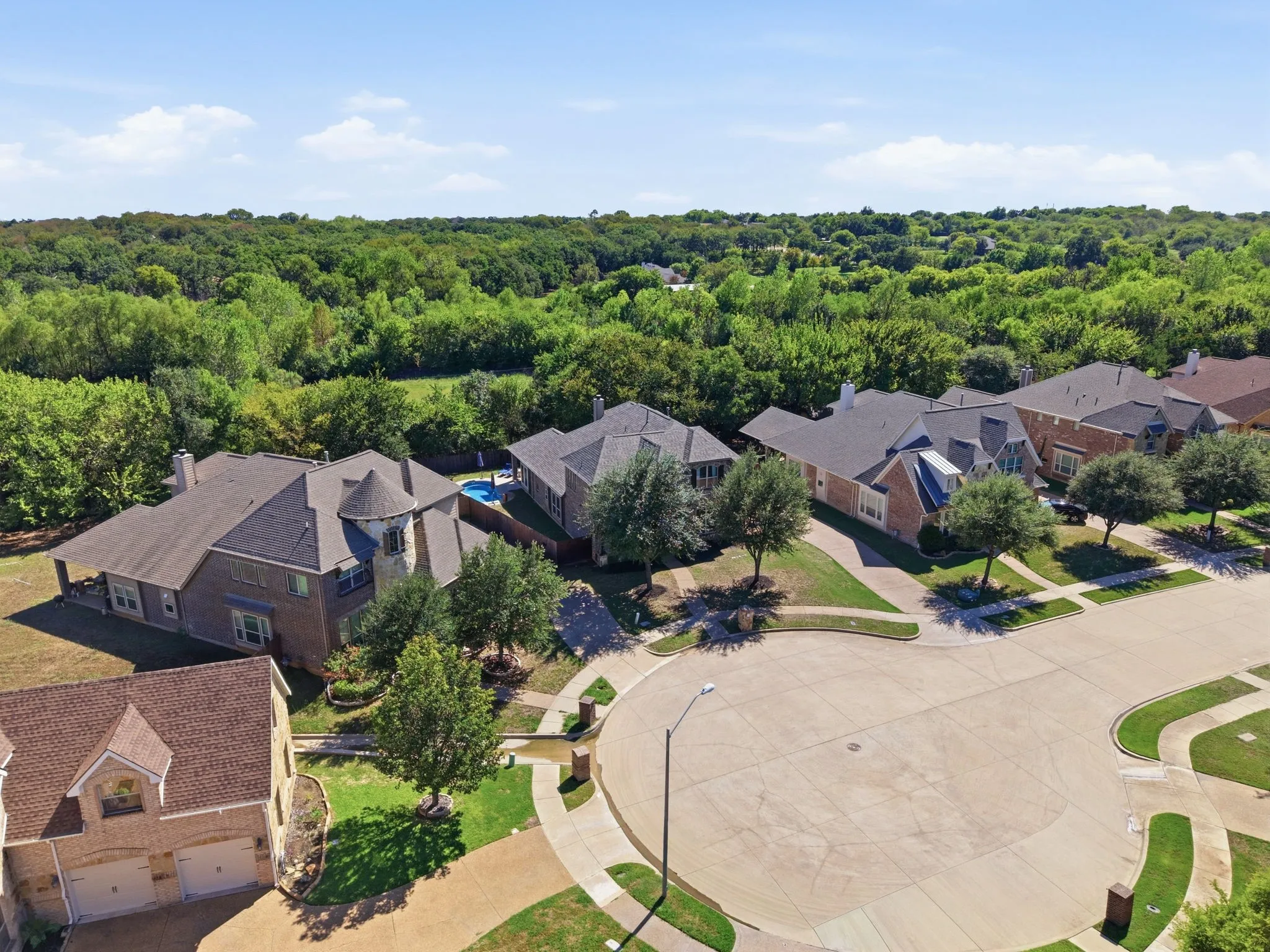 Elevated view showcasing the home's location at the end of a cul-de-sac with a wooded backdrop behind the property.
