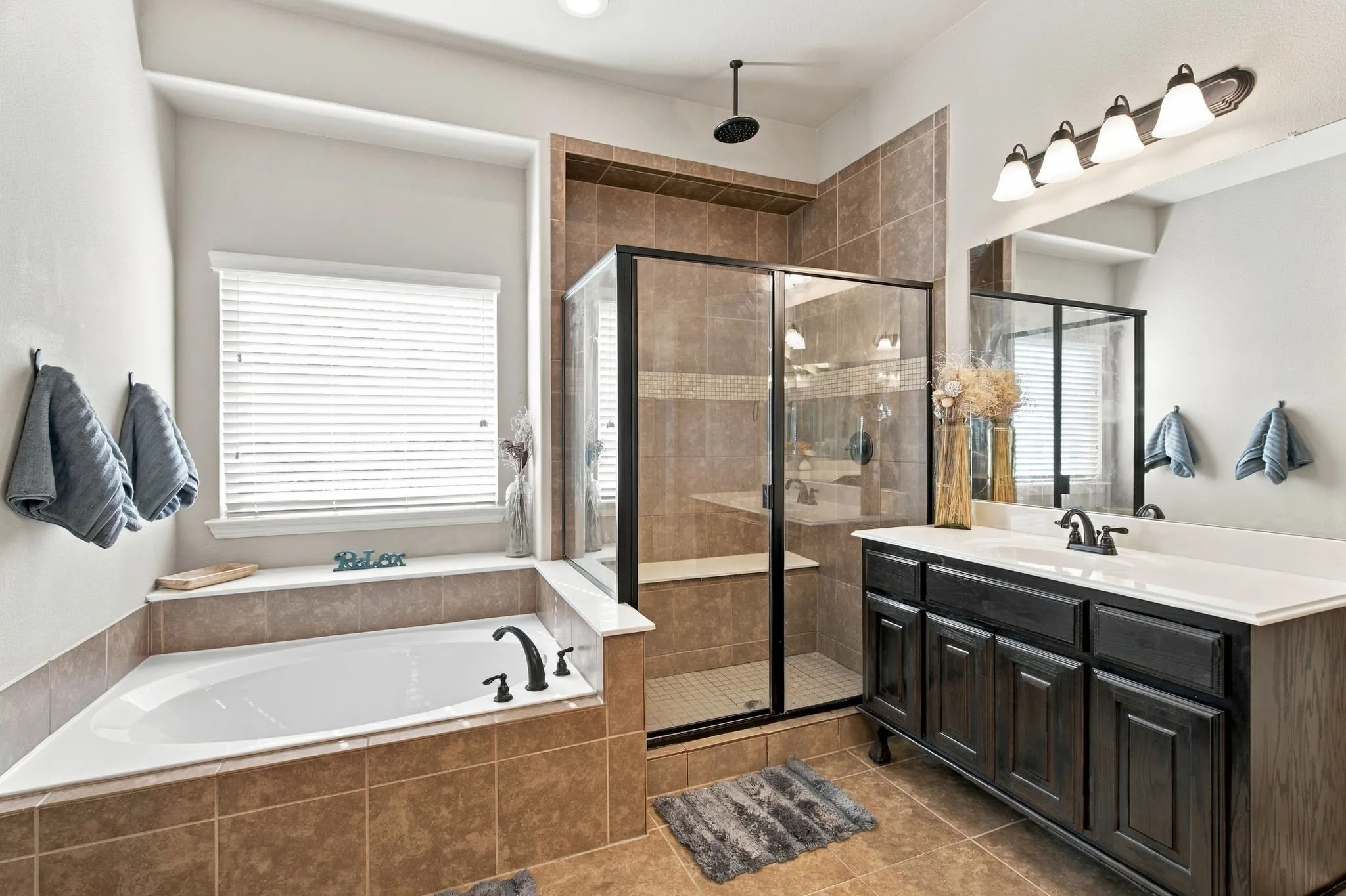 Relax in the separate soaking tub positioned beneath a large window, with an adjacent tiled shower and additional vanity storage completing the space.