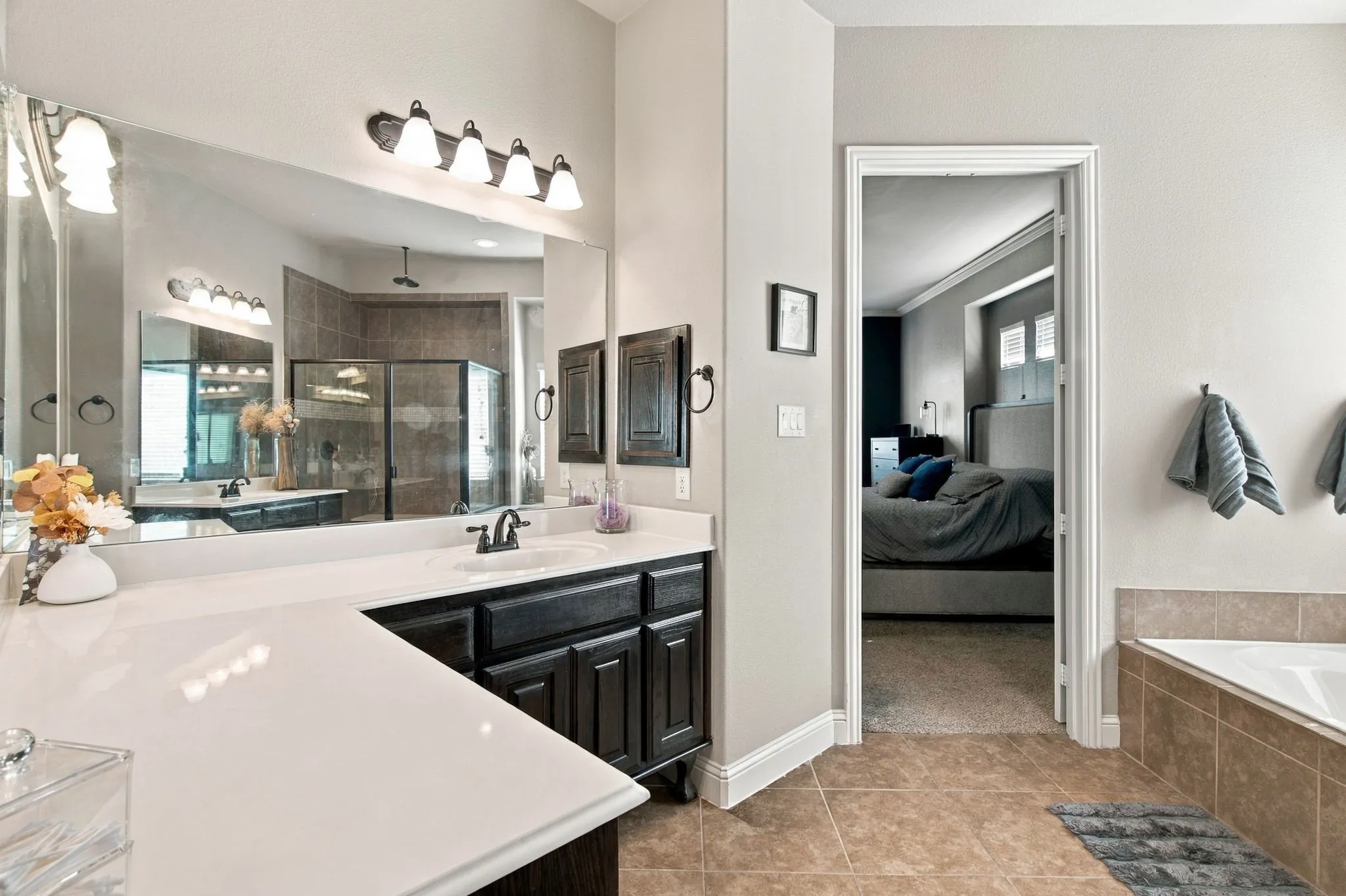Expansive second vanity area featuring generous counter space, dark wood cabinetry, a large wall mirror, and multiple light fixtures for everyday convenience.