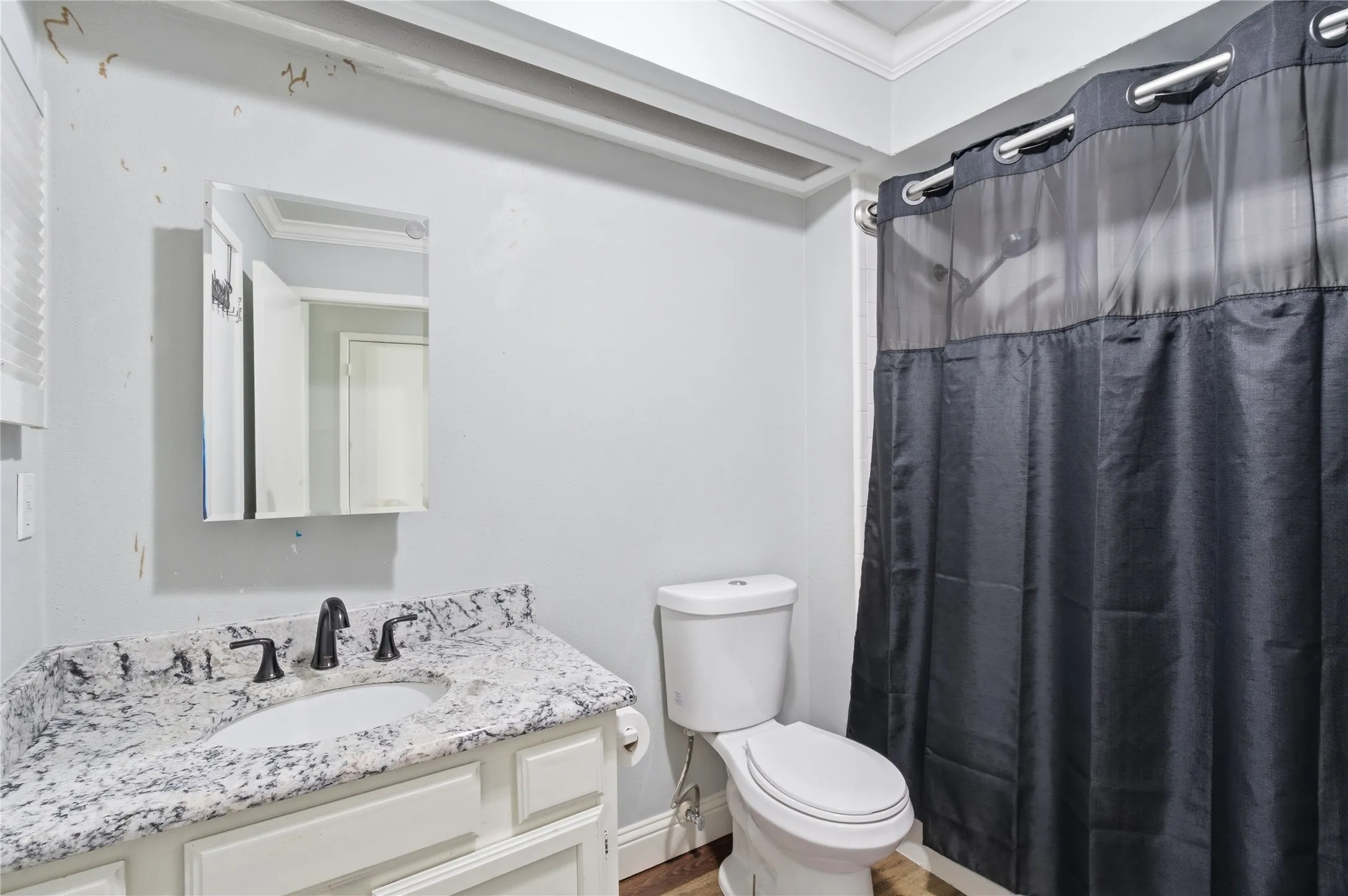 White vanity with stone countertop, undermount sink, and dark-finish faucet