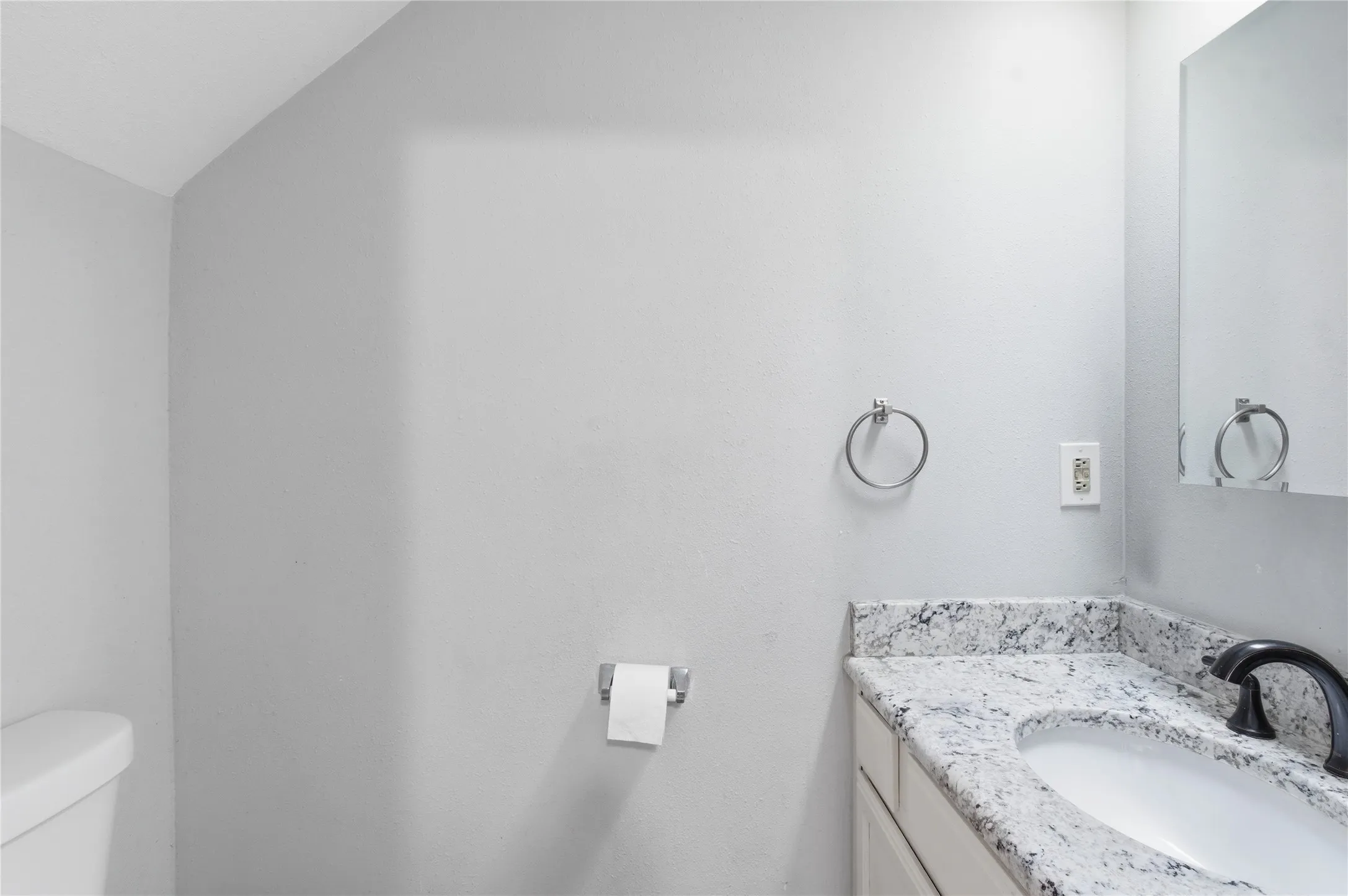 Vanity with a granite countertop, undermount sink, and dark-finish faucet