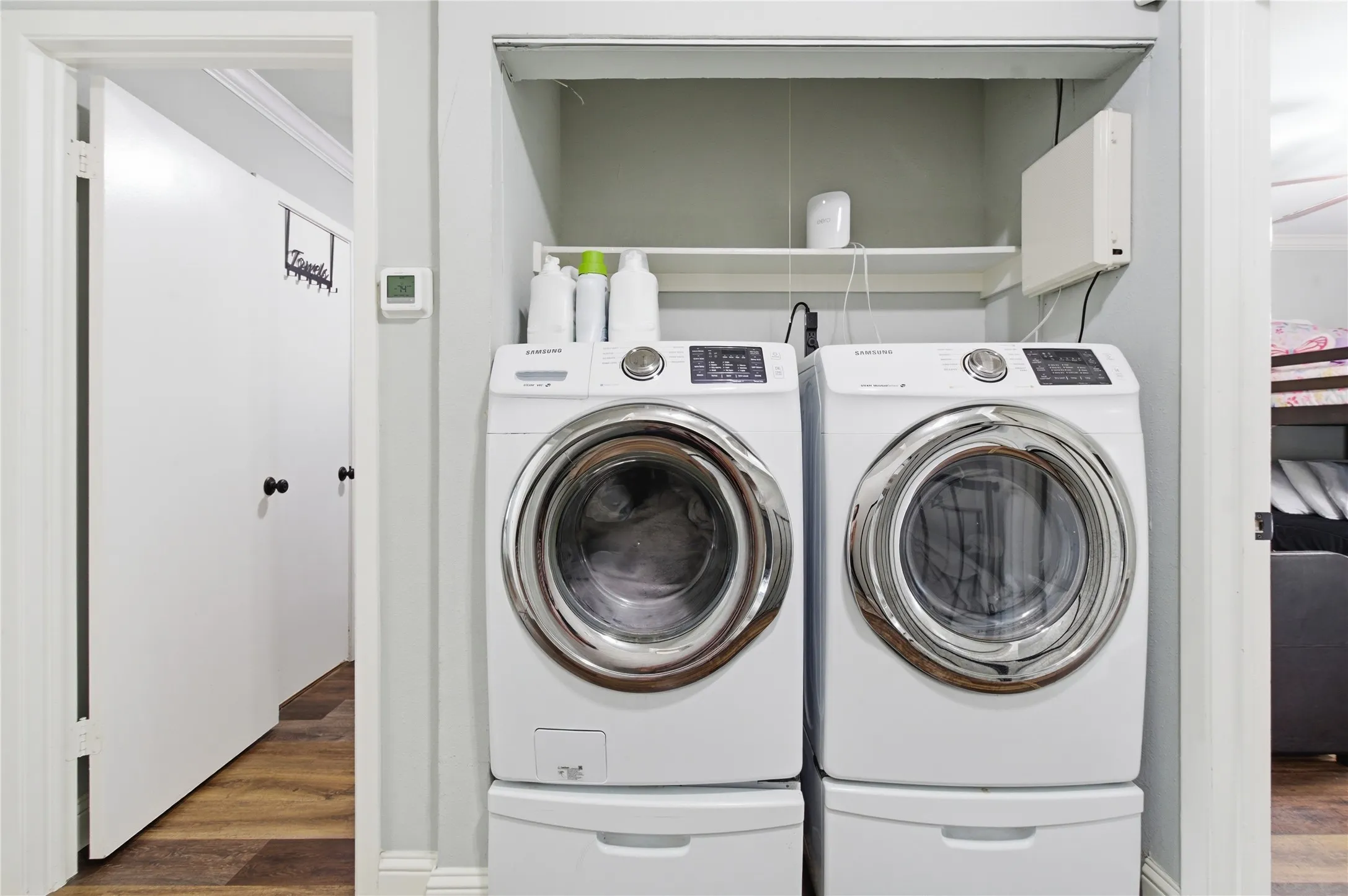 Dedicated laundry area featuring a built-in shelf and wood-finish flooring