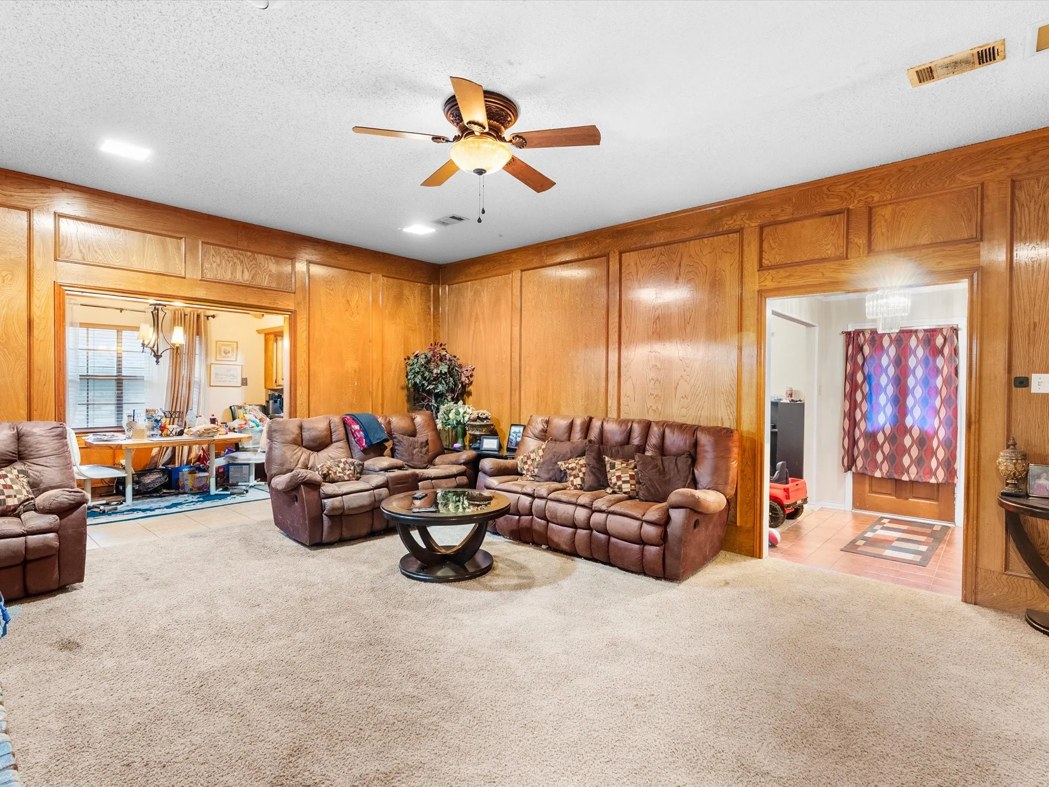 Wood-paneled walls with decorative trim, recessed lighting, and a ceiling fan