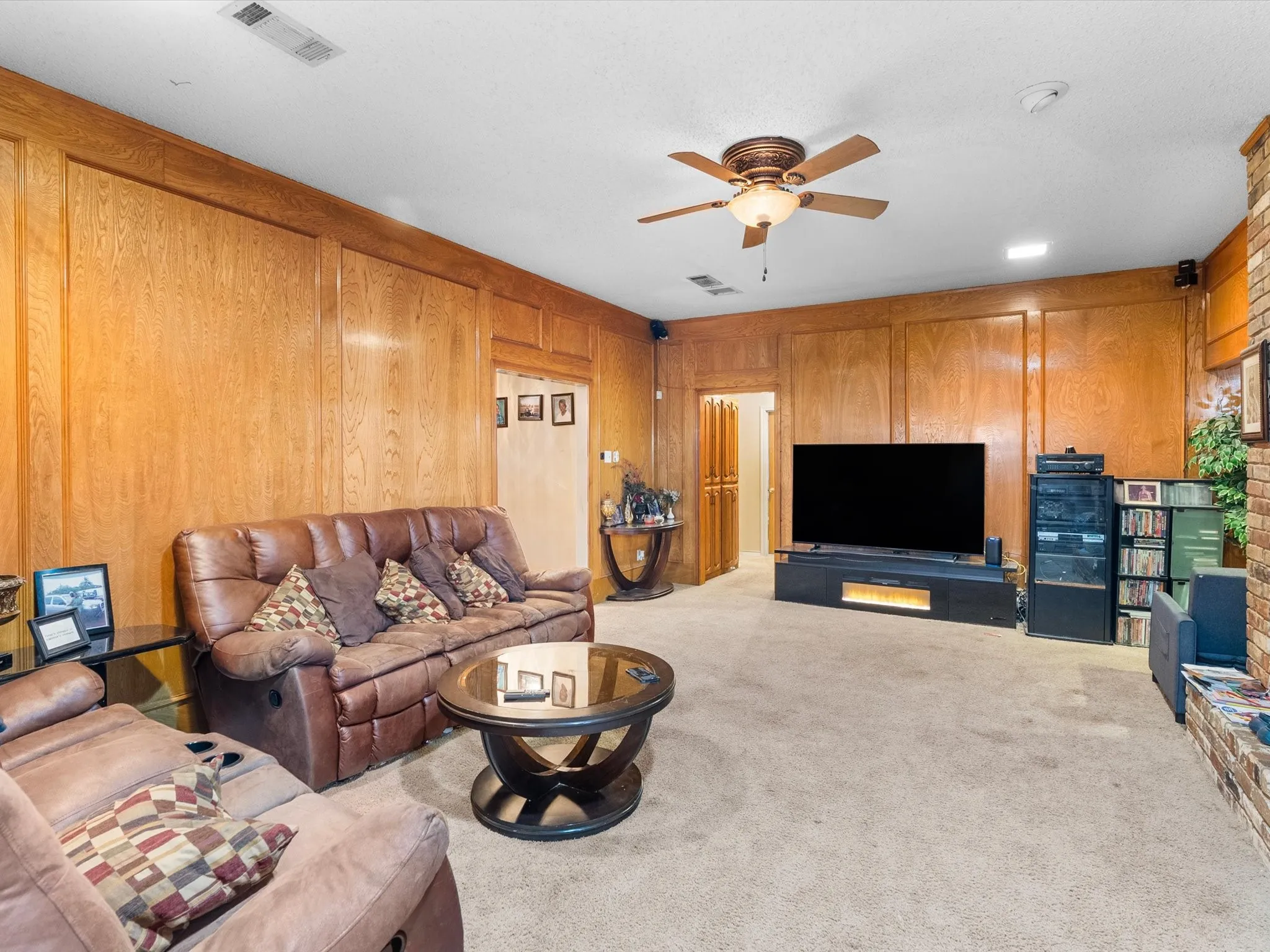 Wood paneling throughout, ceiling fan with integrated lighting, recessed lighting, and carpeted flooring