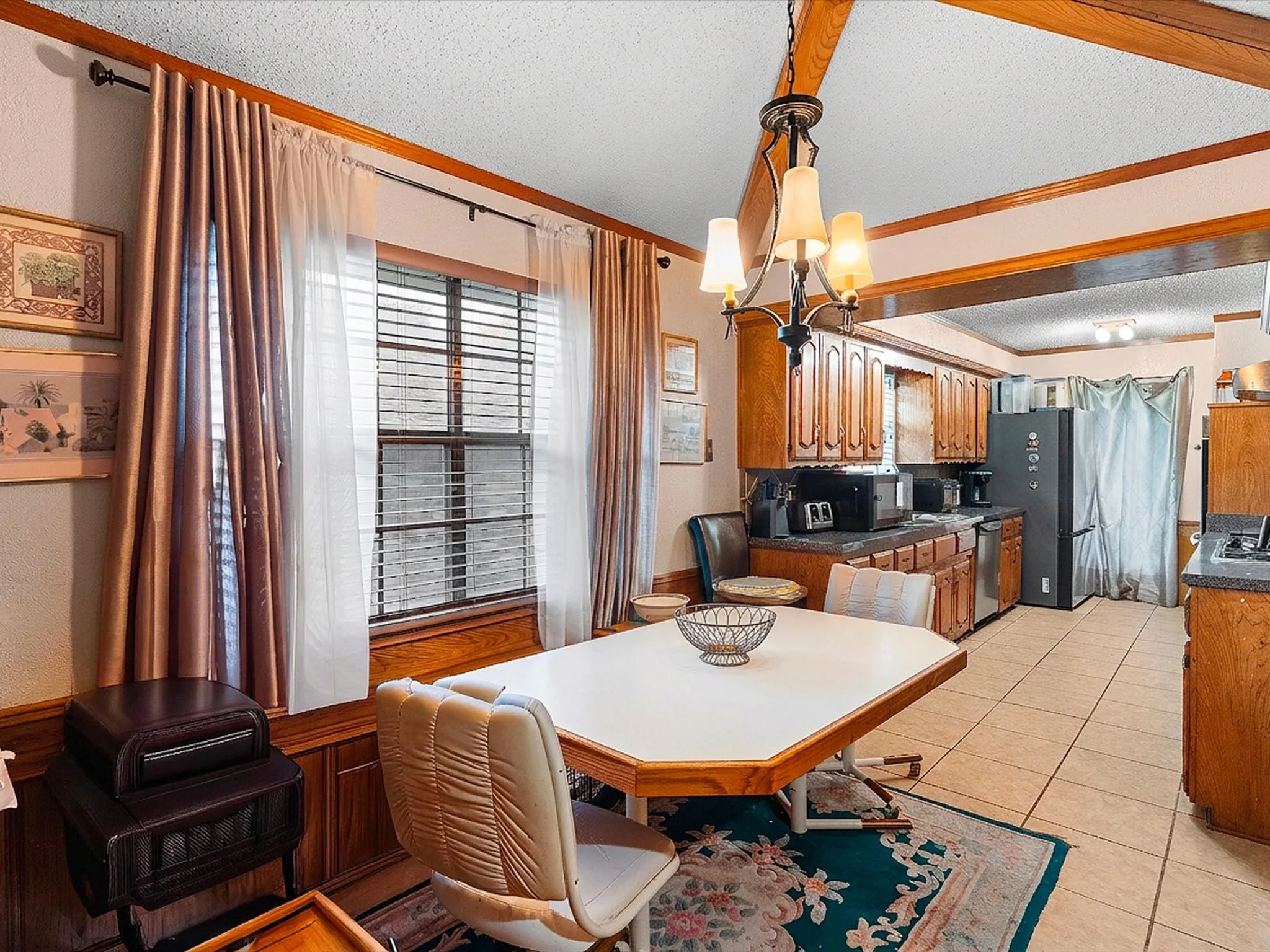 Wood-finish ceiling beams, an ornamental chandelier, and wood-paneled walls