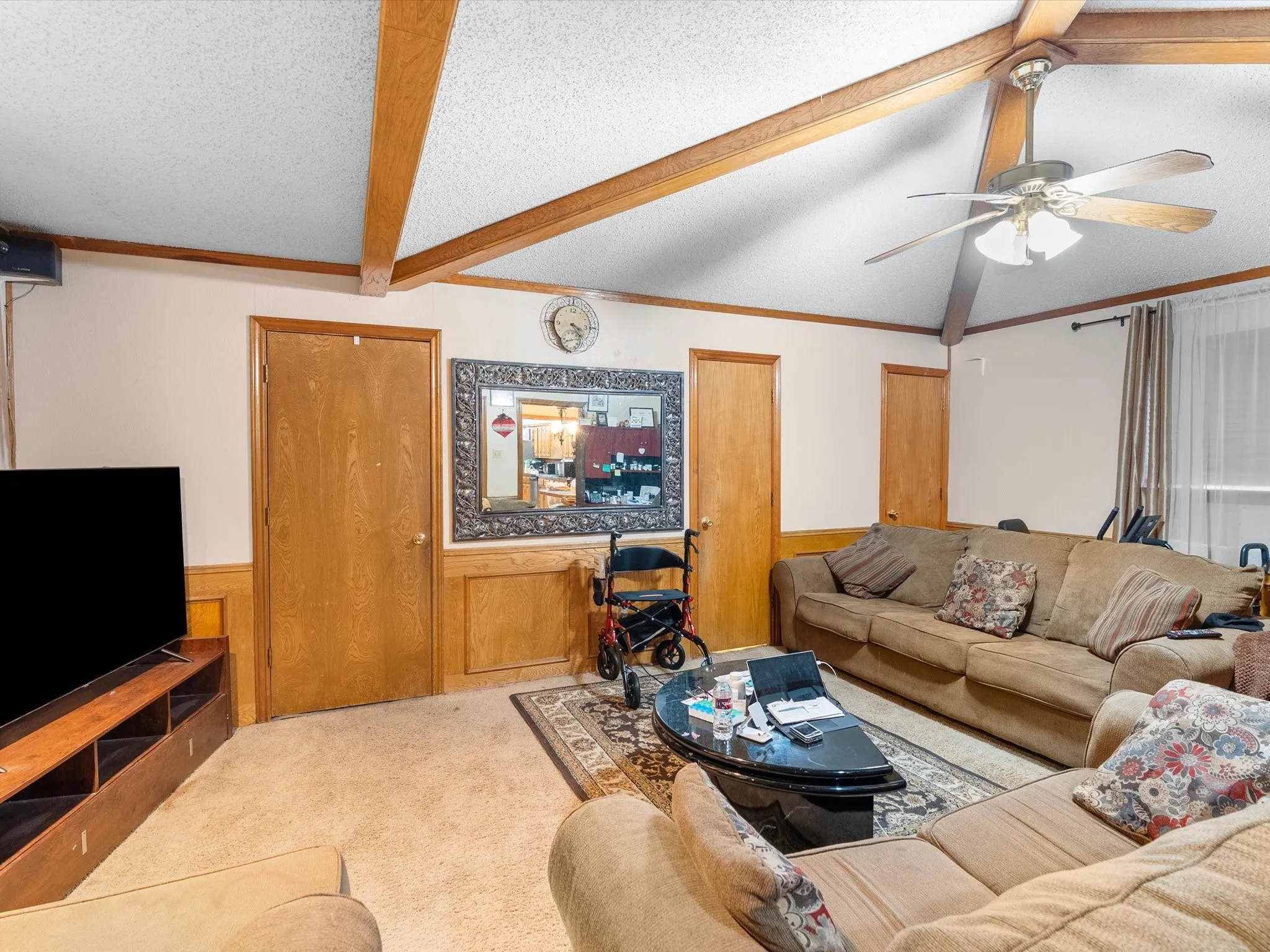 Vaulted ceiling with exposed wood beams, wood-finish doors, and wainscoting
