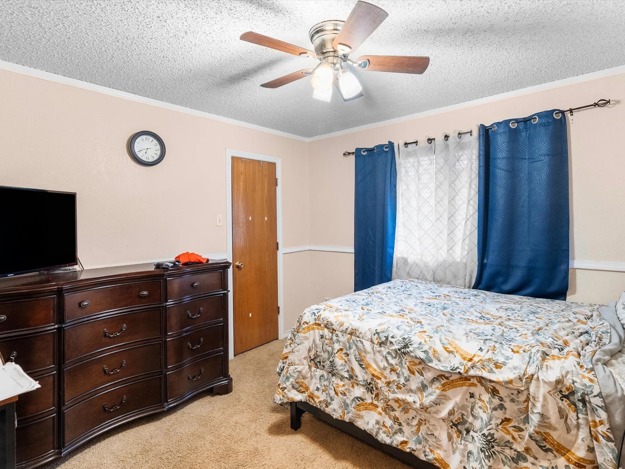 Ceiling fan with light fixture, textured ceiling, light-toned walls