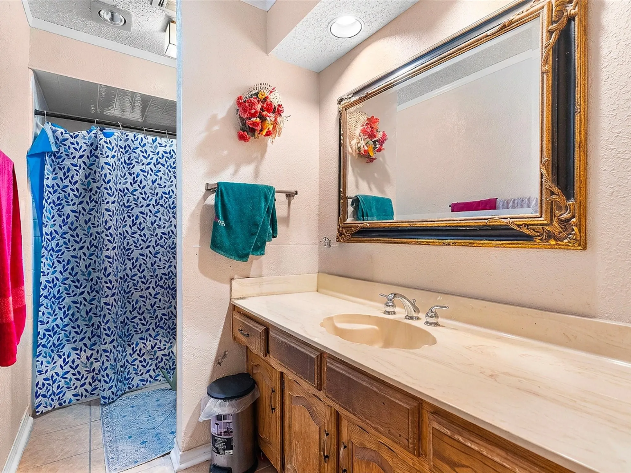 Bathroom featuring a vanity with a light-toned countertop, integrated sink, and an ornate framed mirror