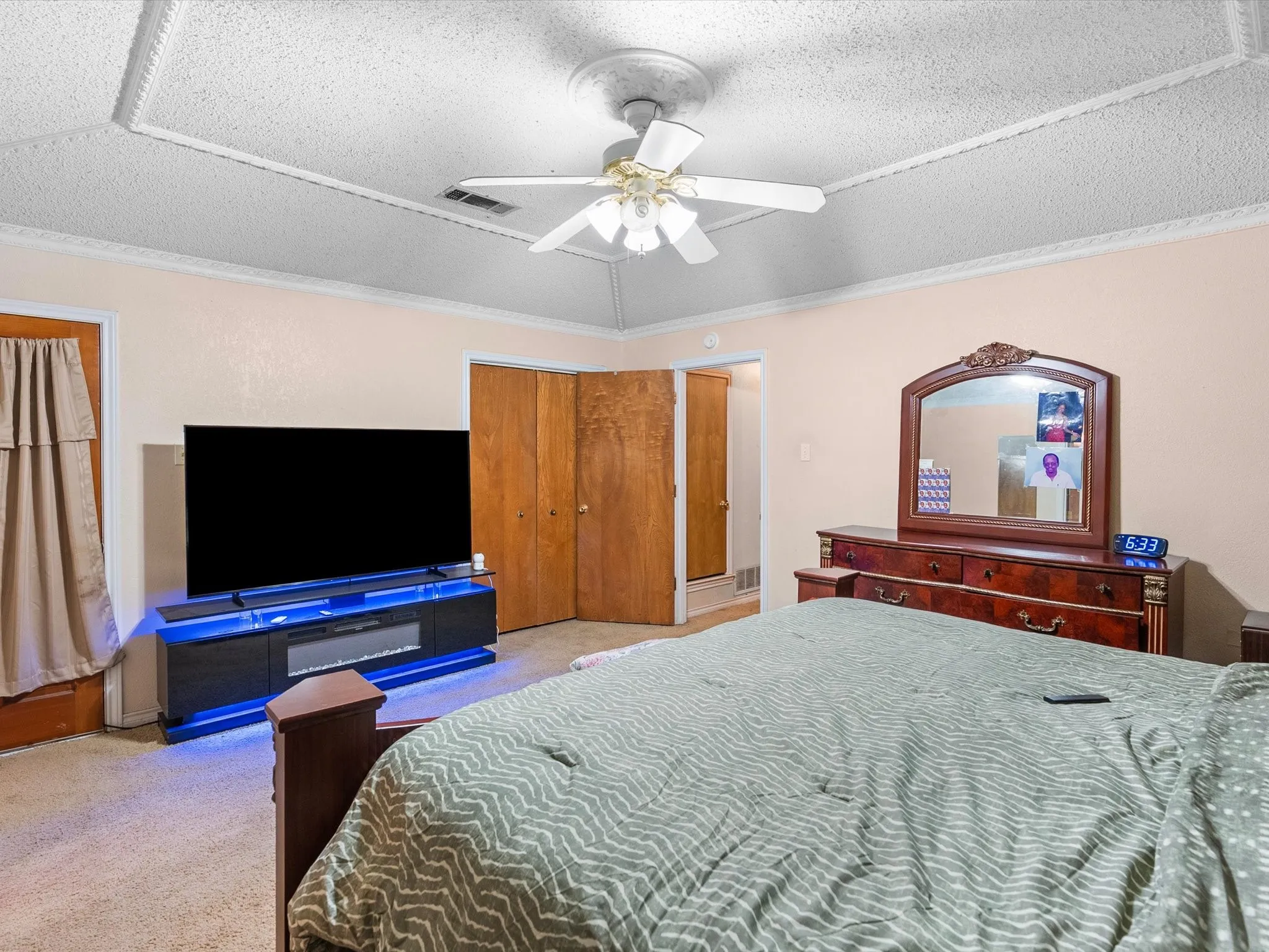 Tray ceiling with decorative trim, ceiling fan, and carpeted flooring