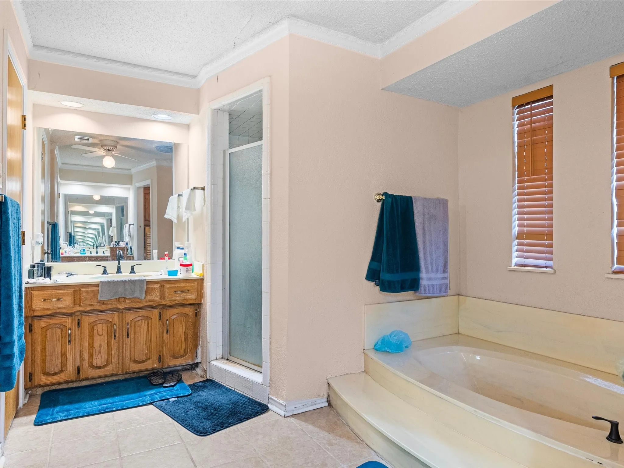 Dual vanity with wood cabinetry, large mirror, and tiled flooring