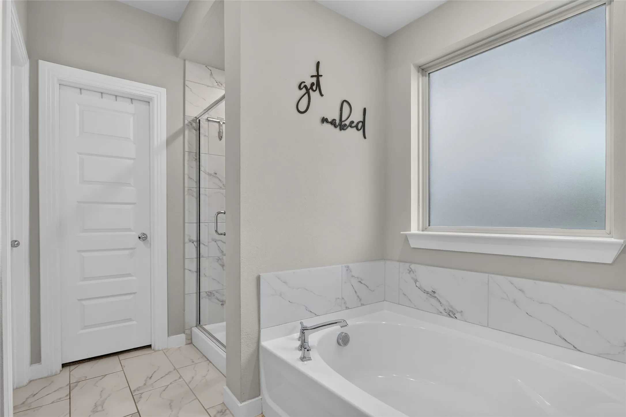 Soaking tub with a chrome faucet, surrounded by large format wall tile