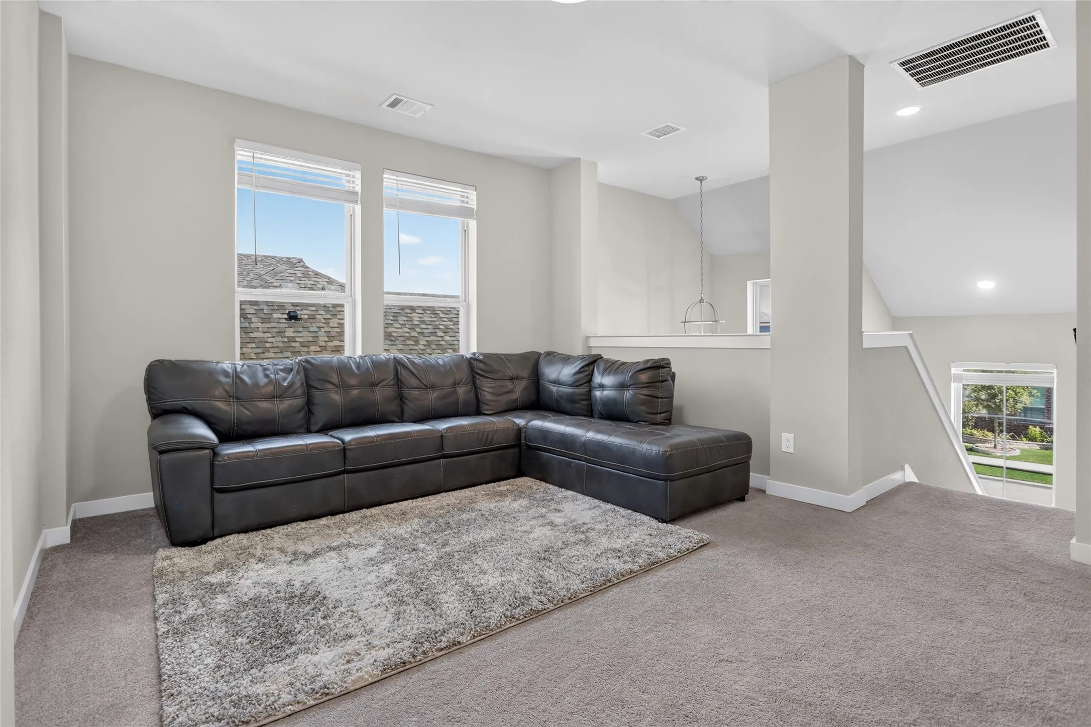 Carpeted room featuring dual windows, recessed lighting, and a partial wall with a railing