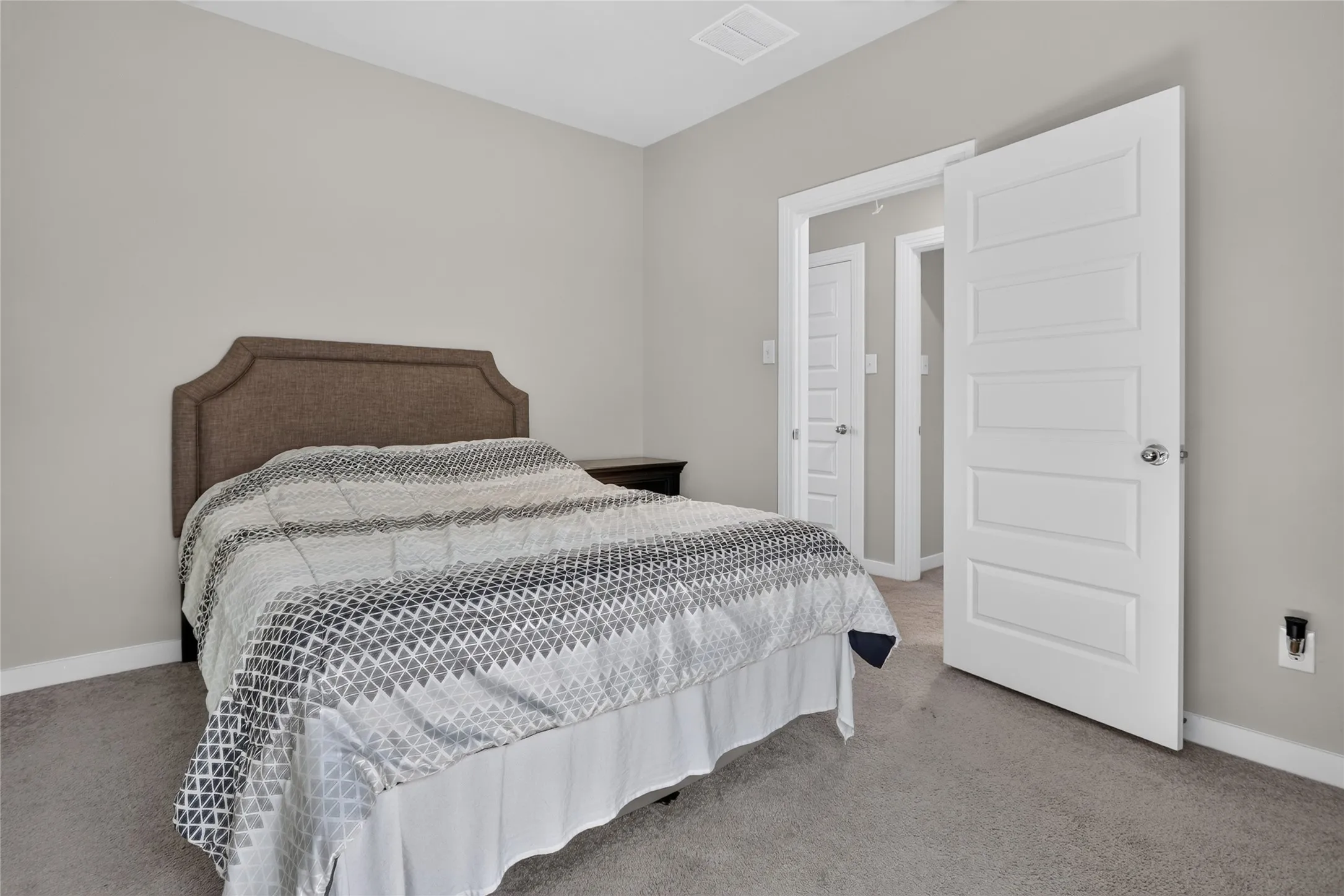 Light gray wall paint, gray carpet flooring, white paneled doors, and a ceiling vent
