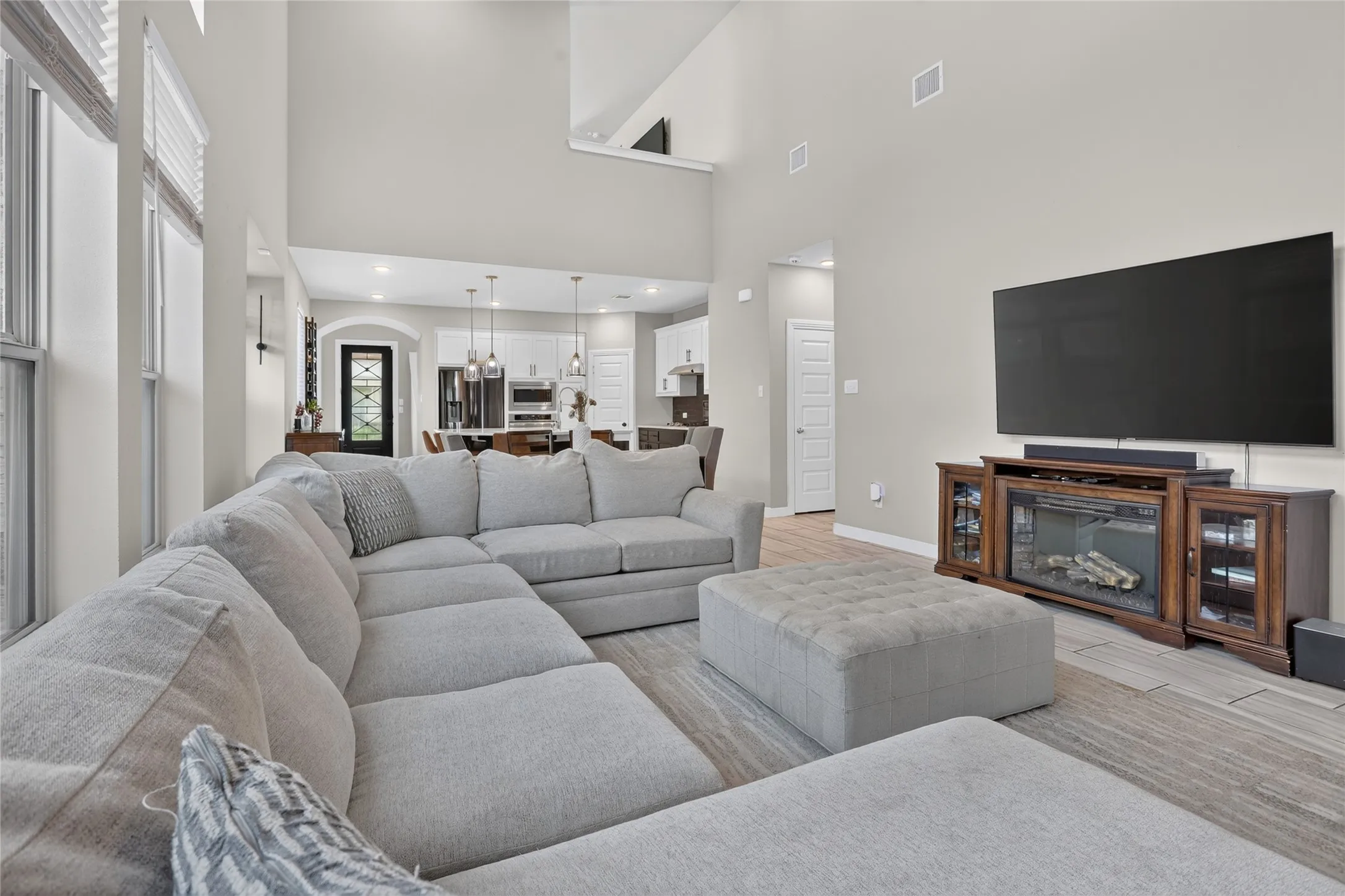 Vaulted ceilings with abundant natural light, wood-finish flooring, and a built-in media console with an electric fireplace