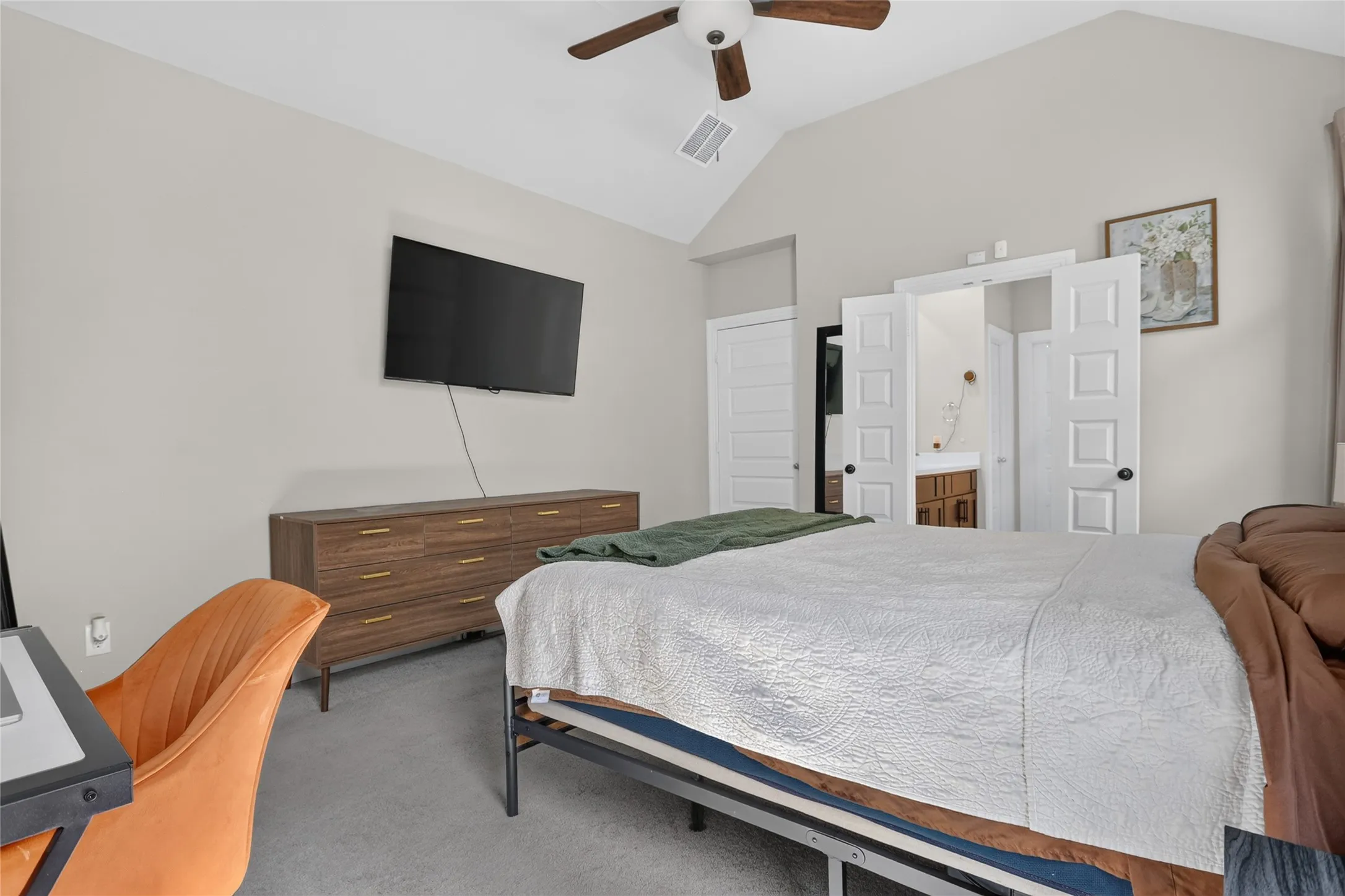 Vaulted ceiling with a ceiling fan, wall-mounted television, and neutral wall paint