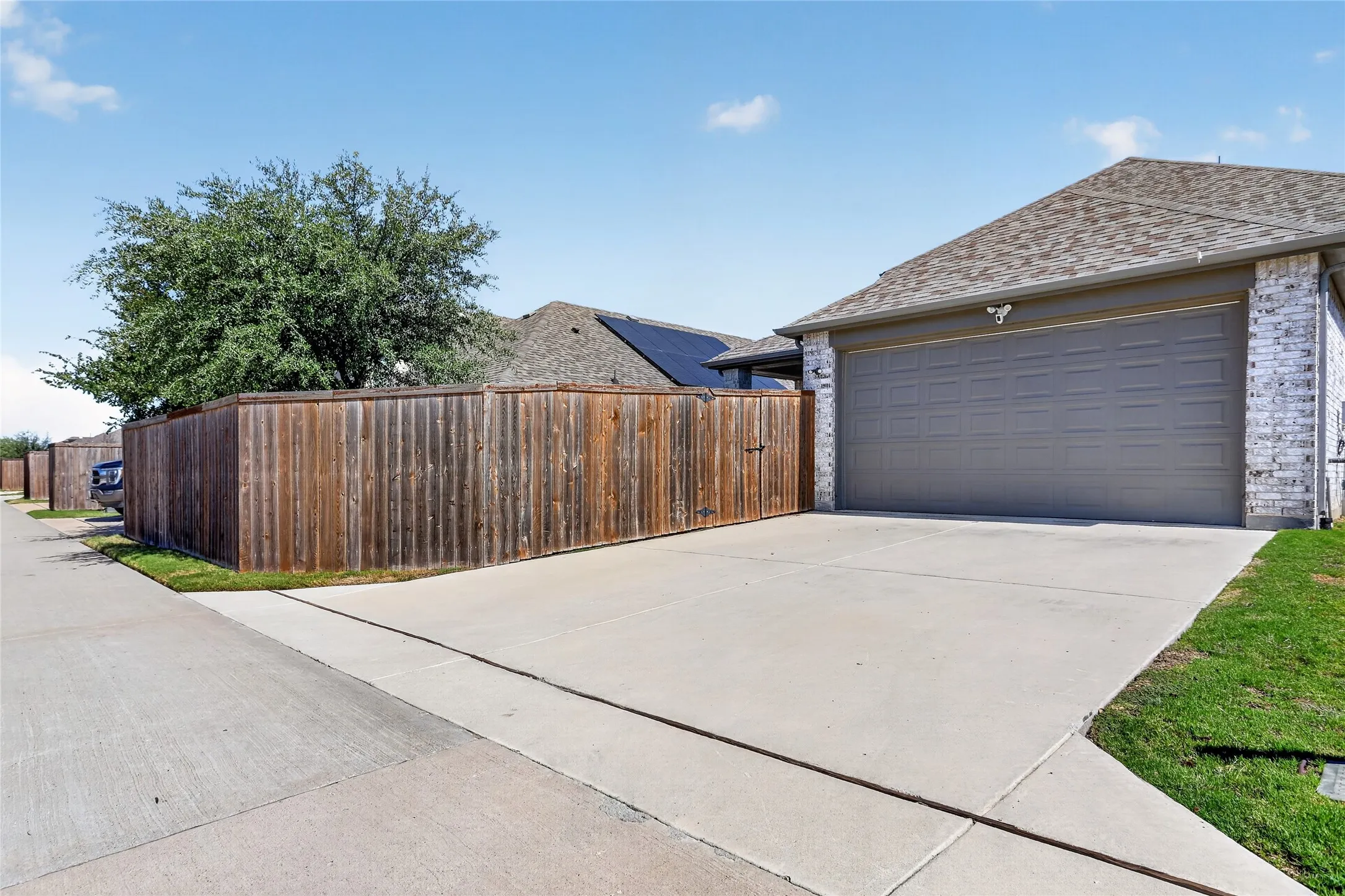 Attached garage with a gray door, concrete driveway, and brick exterior