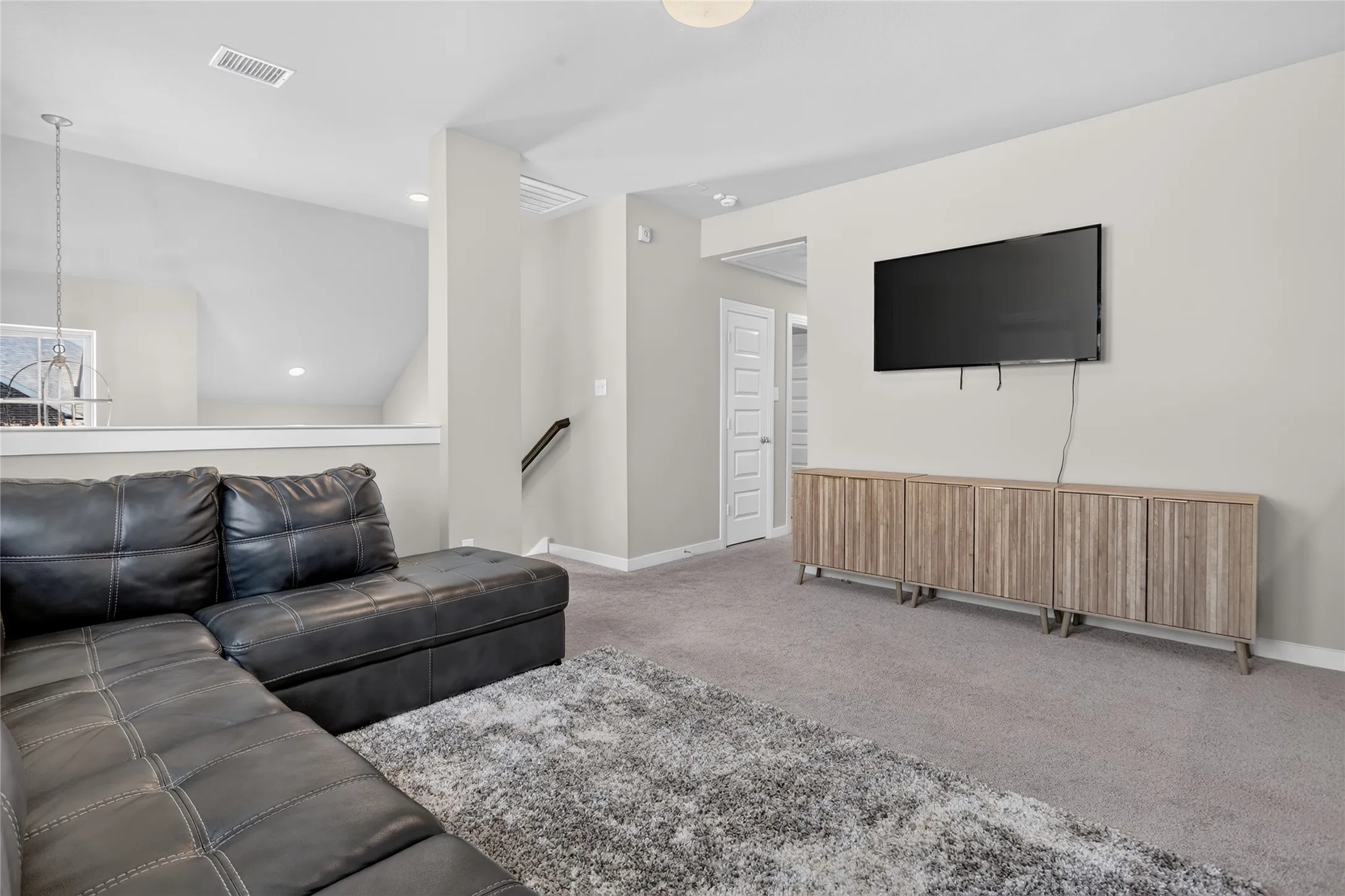 Carpeted room with vaulted ceiling and recessed lighting