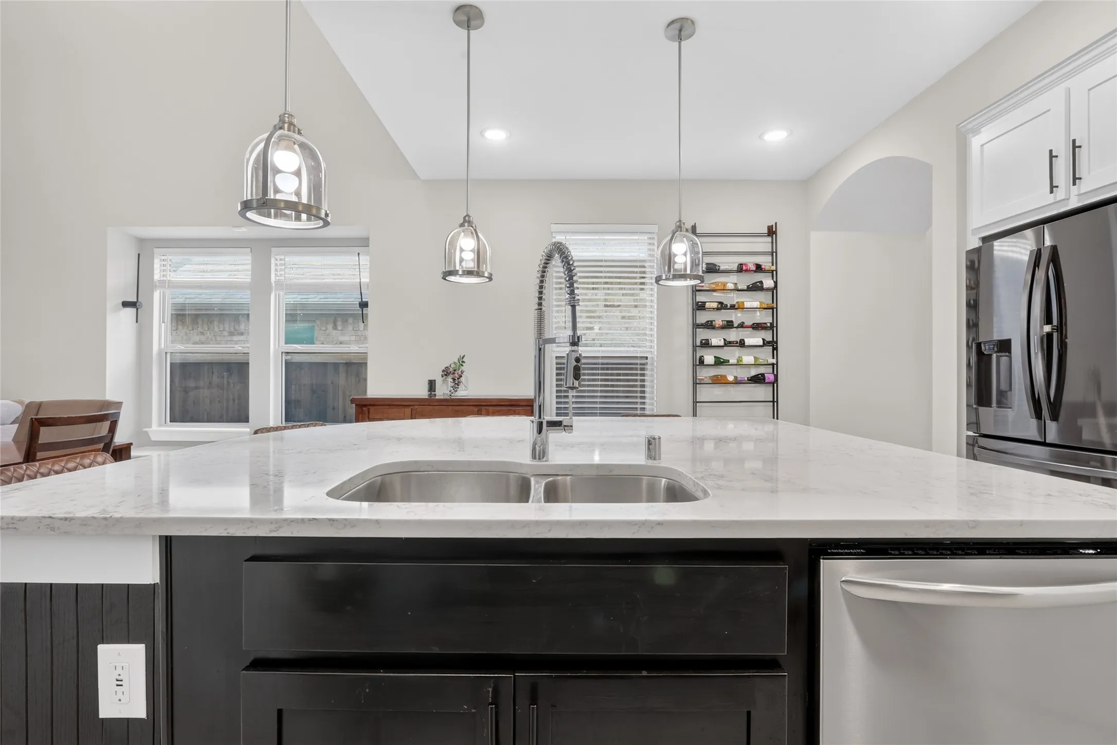 Kitchen island featuring a dual basin sink, pull-down faucet, and light-toned countertop