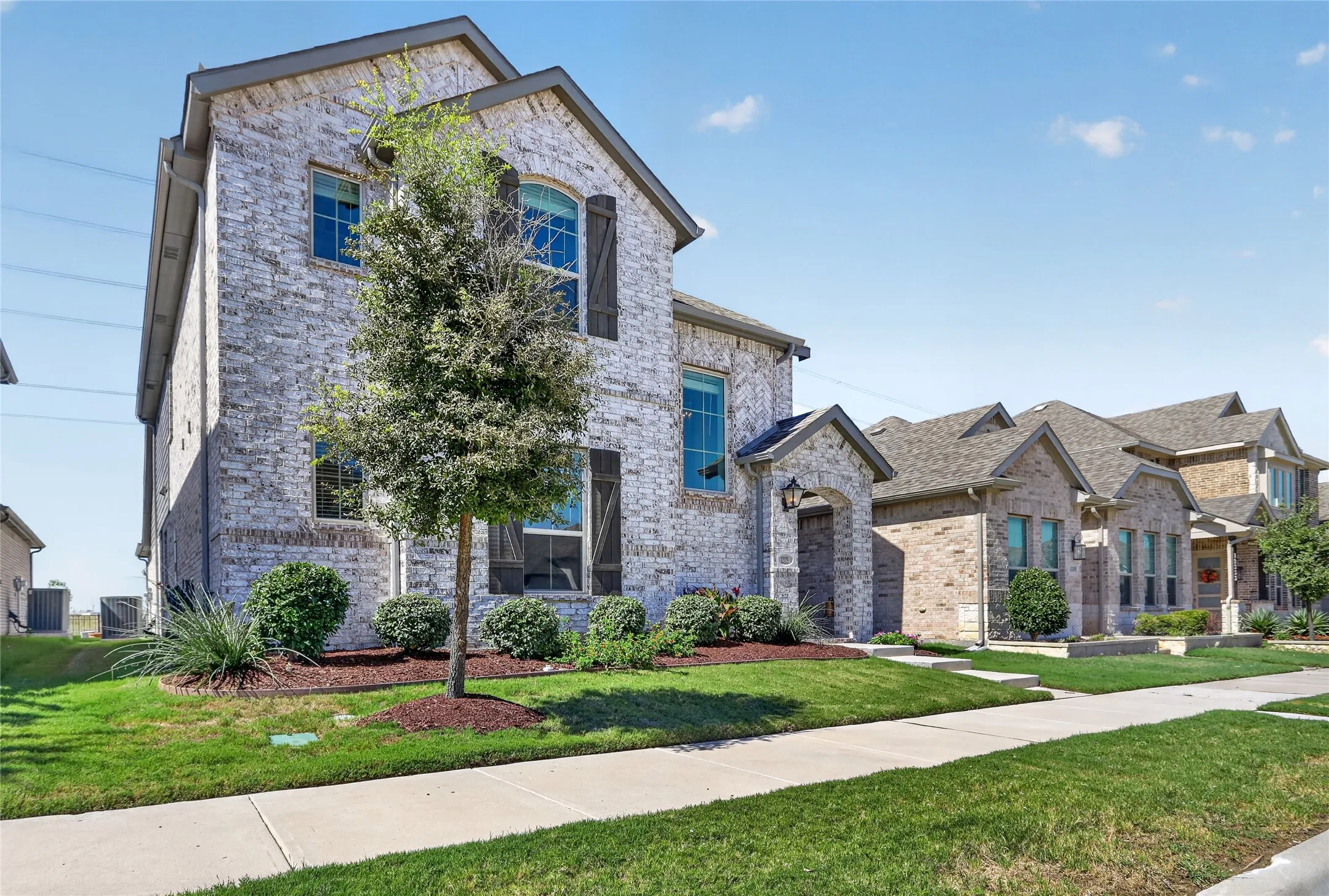 Two-story brick exterior with gabled roof lines and dark shutters