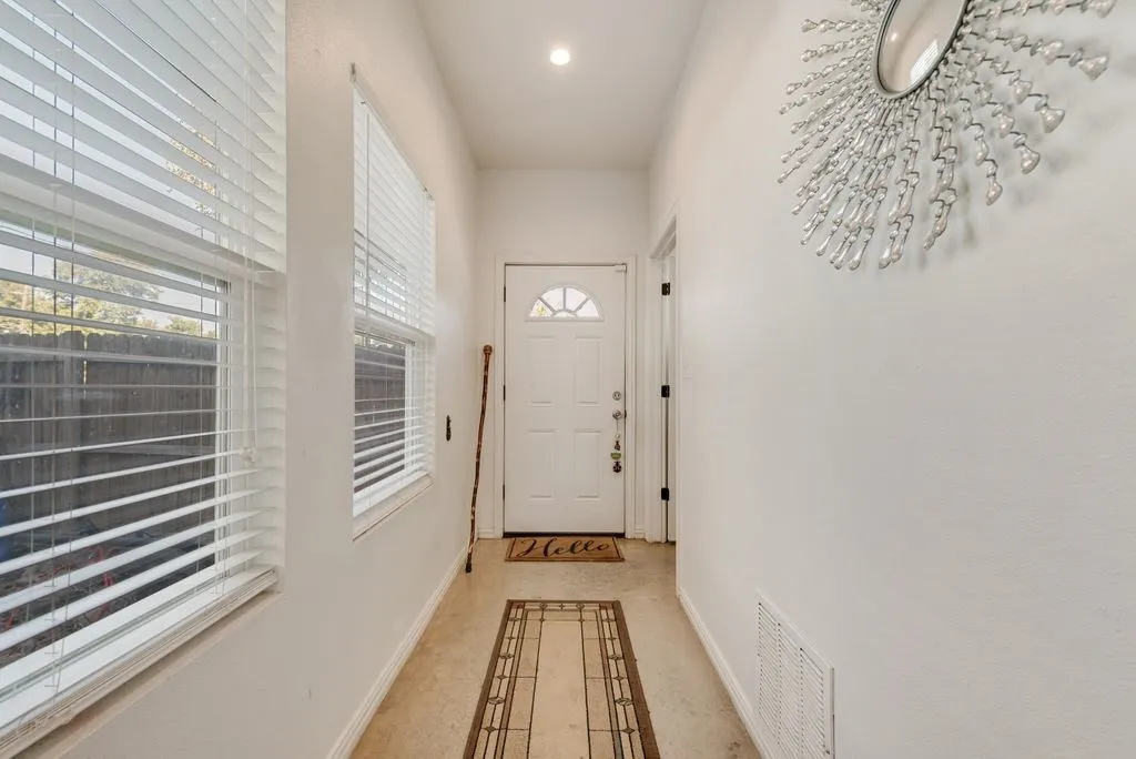 Recessed lighting illuminates the entry hall featuring a solid entry door with a decorative arch window