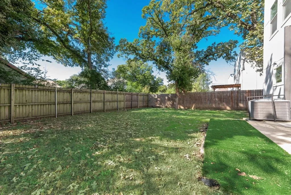 Expansive backyard featuring a partial artificial turf section, natural grass, and a wood privacy fence