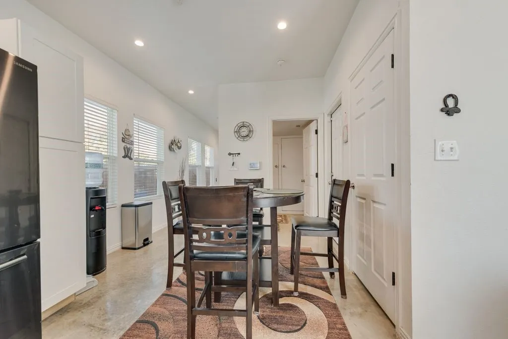 Recessed lighting, multiple windows with blinds, panel doors, and concrete-finish flooring