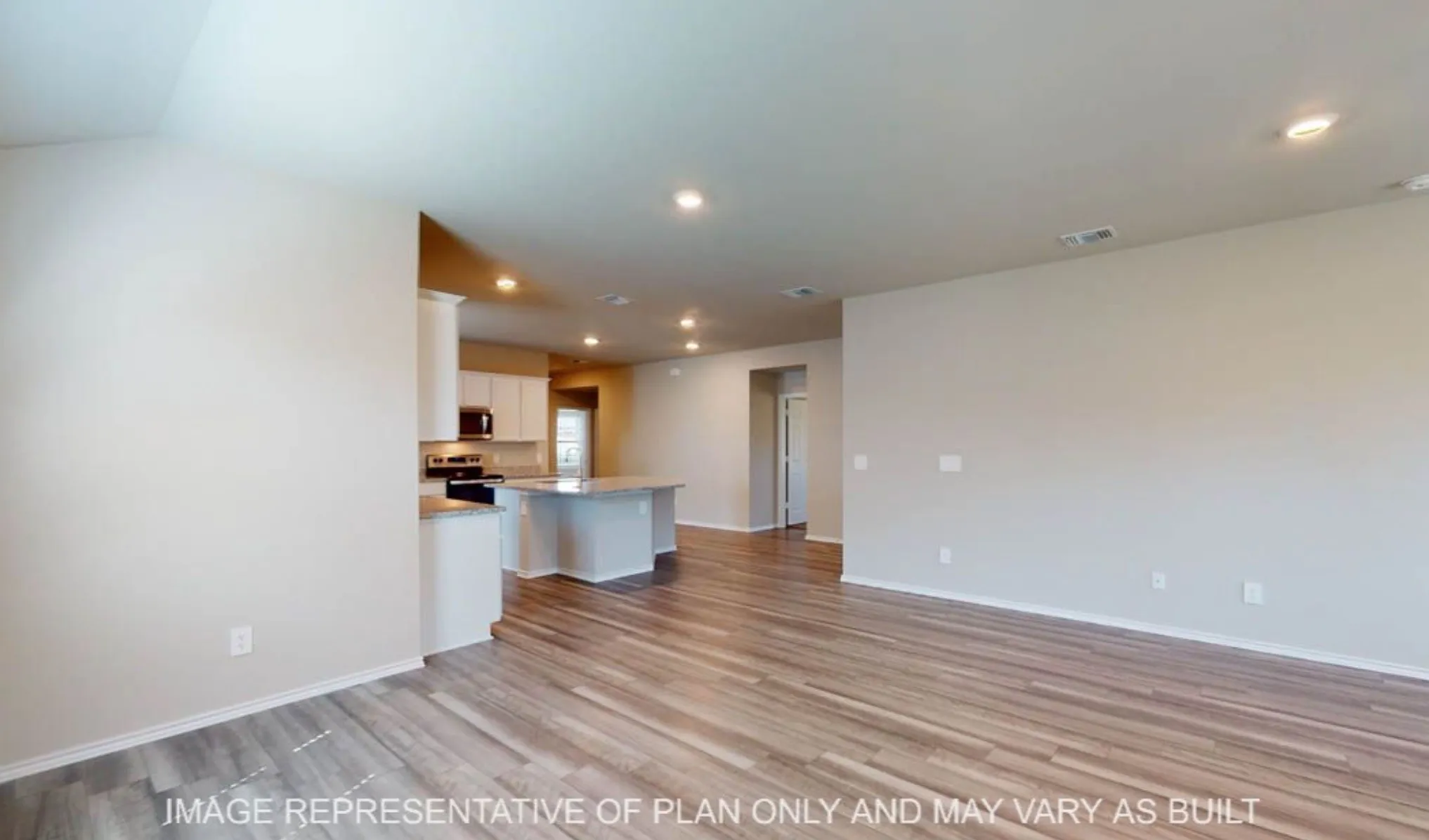 Open-concept living space featuring warm wood-finish flooring, recessed ceiling lighting, and a modern kitchen with white cabinetry and stainless steel appliances