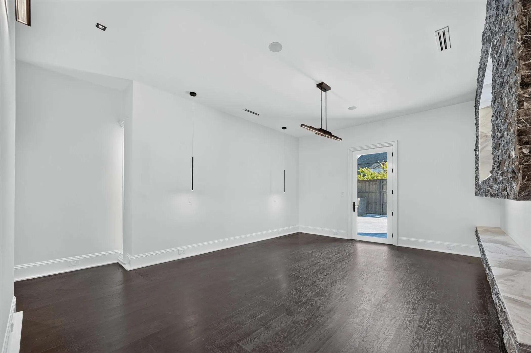 Dark wood-finish flooring with white baseboards, a full-light exterior door, and a built-in stone feature with a stone ledge