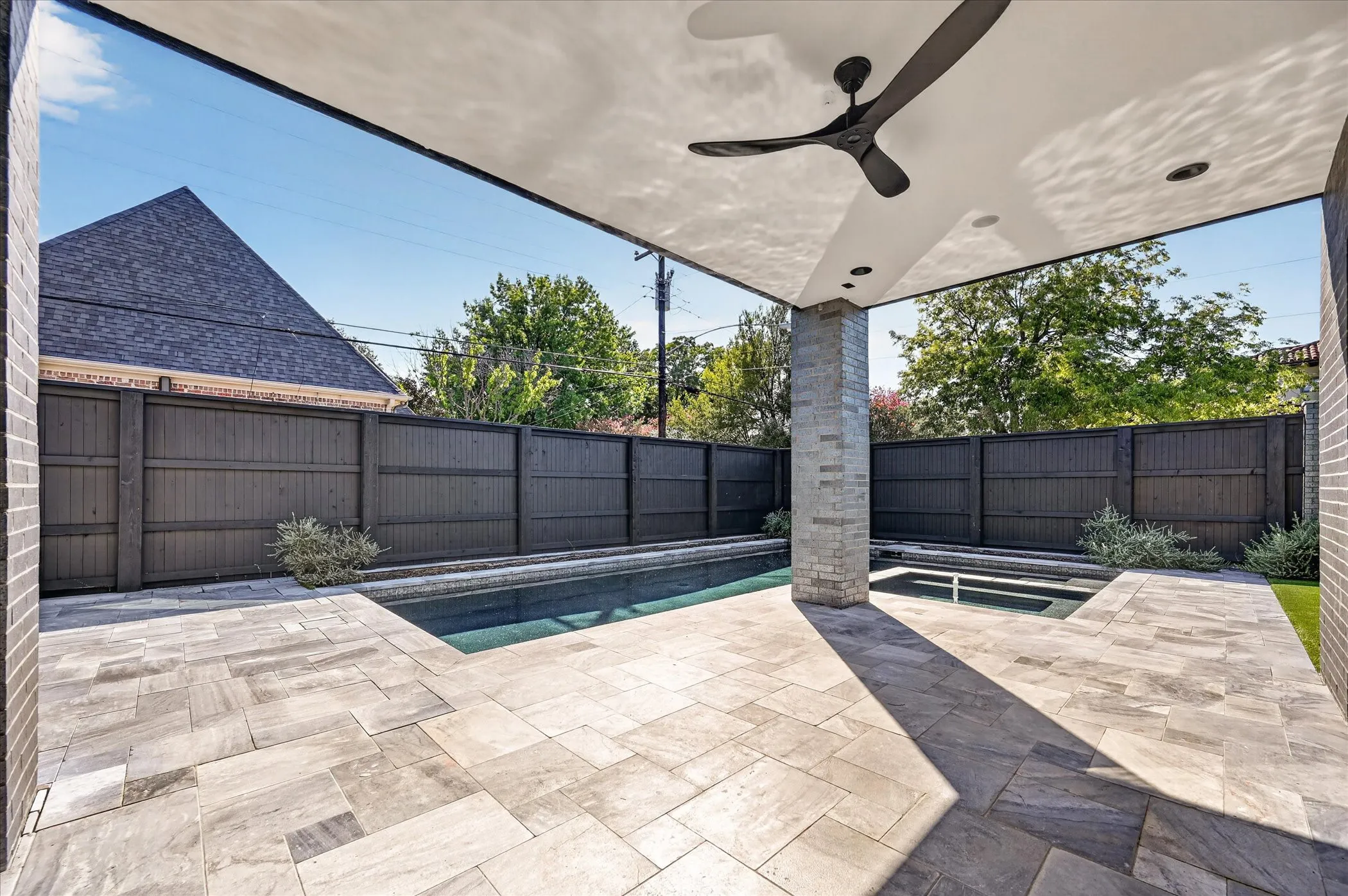 Expansive outdoor patio featuring a covered area with a ceiling fan and recessed lighting, a built-in pool, and a spa