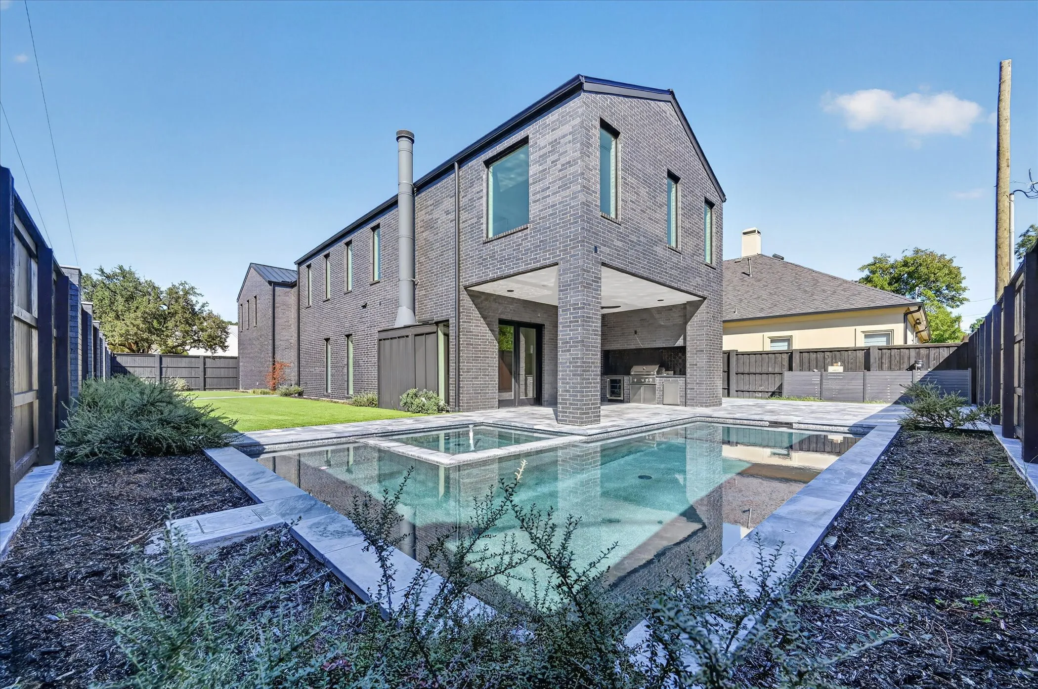 Modern architectural design featuring dark brick masonry and an integrated outdoor kitchen