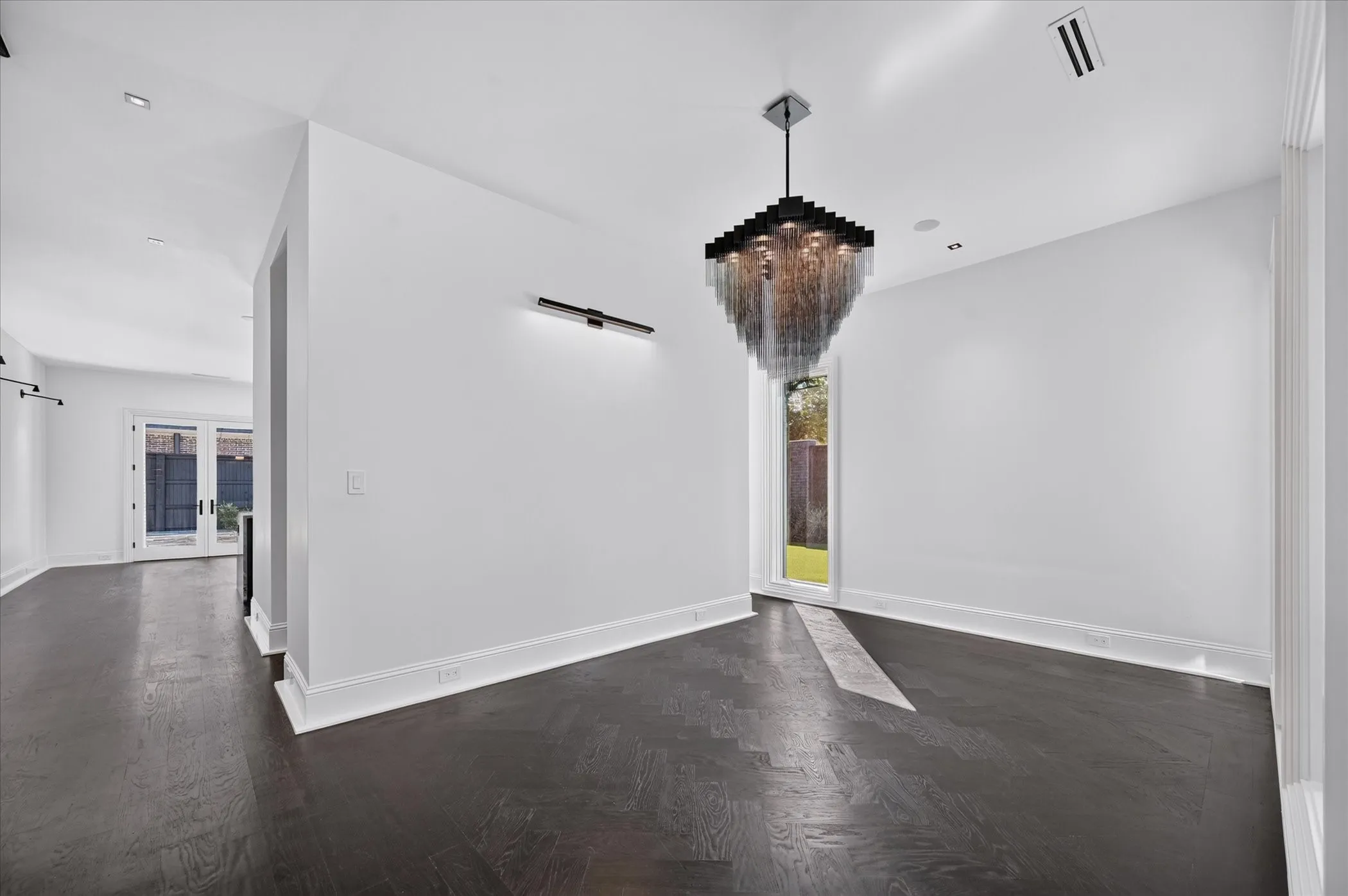 Dark wood-finish flooring with a light-colored inset, modern chandelier, recessed lighting, and a linear wall sconce