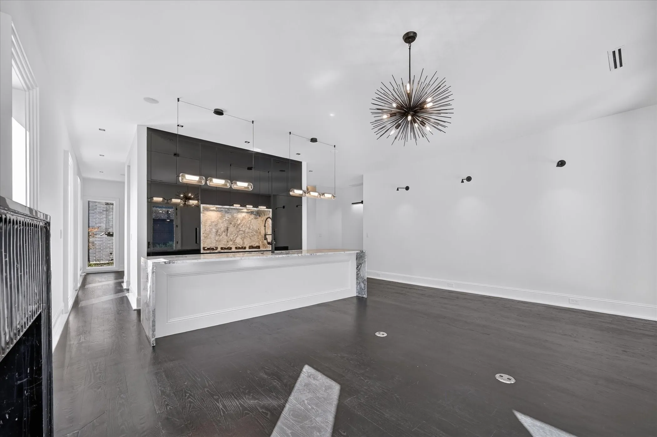 Dark wood-finish flooring, a contemporary sputnik chandelier, and a built-in bar with stone finish countertop and backsplash
