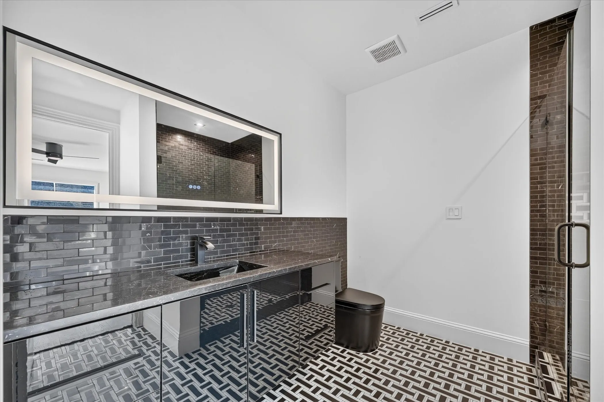 Herringbone tile flooring, dual vessel sinks, and a large illuminated mirror
