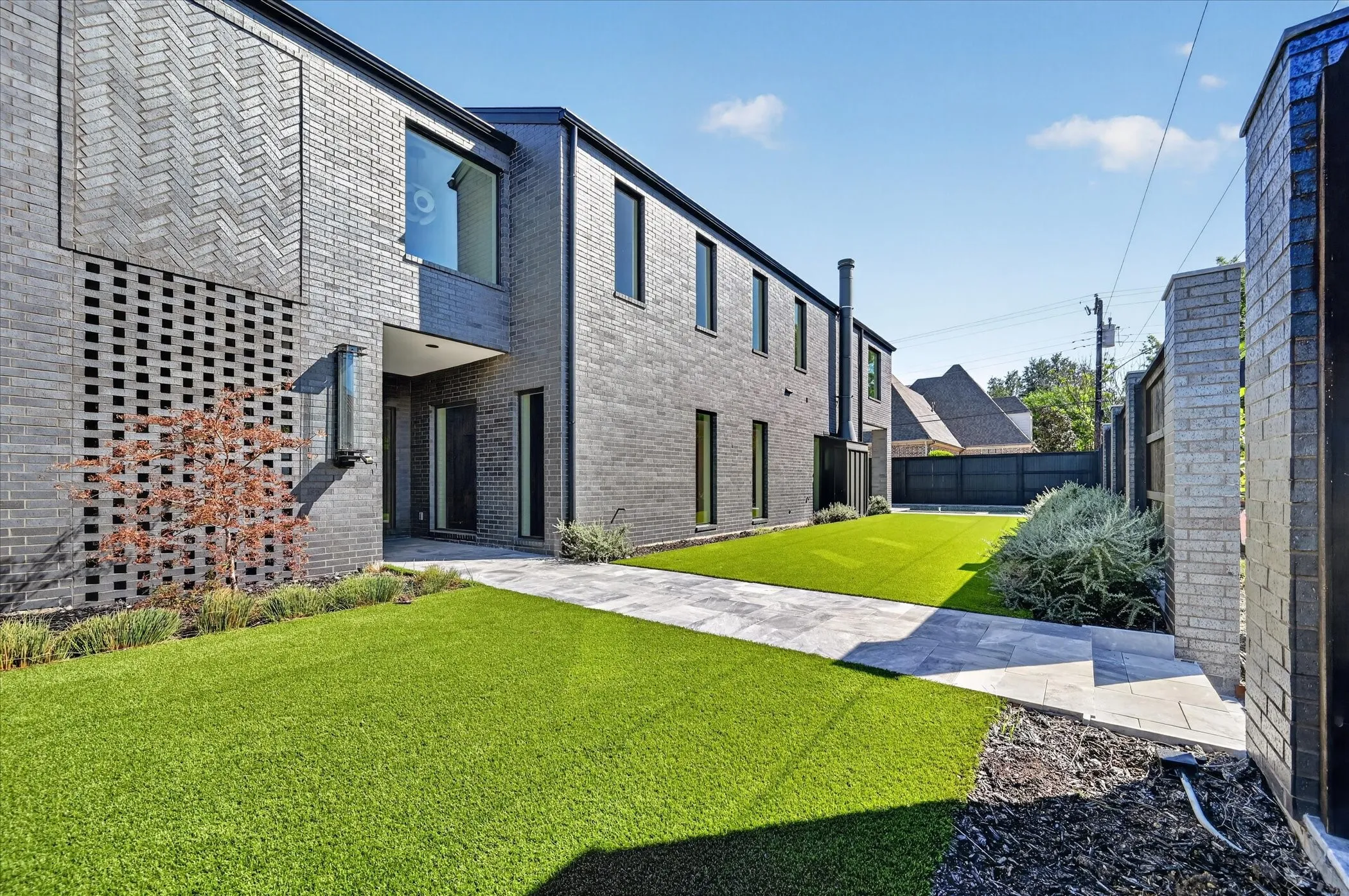 Contemporary brick exterior with unique decorative brickwork, covered entry, multiple windows, and a paved walkway