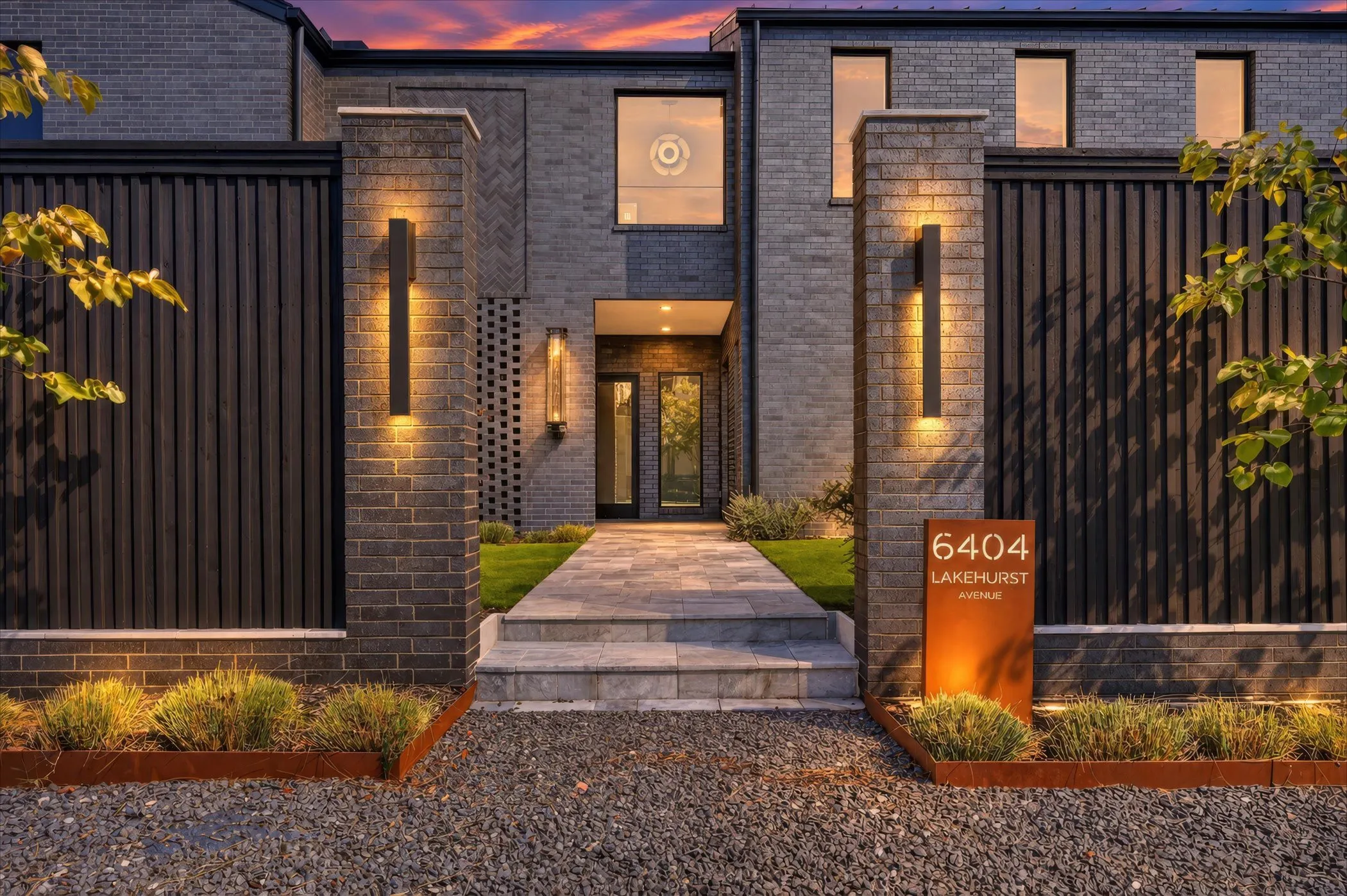 Contemporary facade featuring dark brick, a stone walkway, and integrated exterior lighting