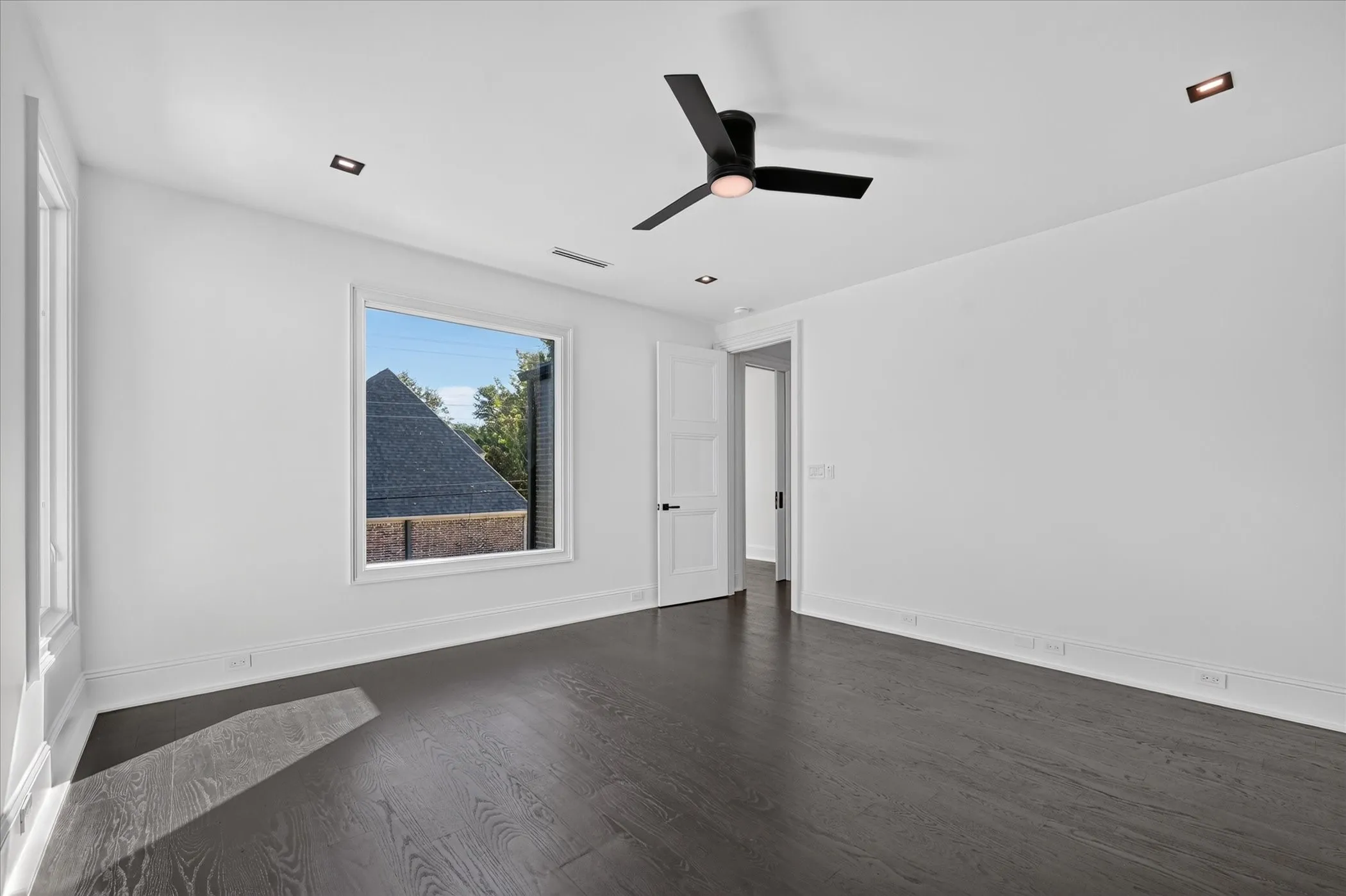 Dark wood-finish flooring with white baseboards, recessed lighting, and a contemporary ceiling fan
