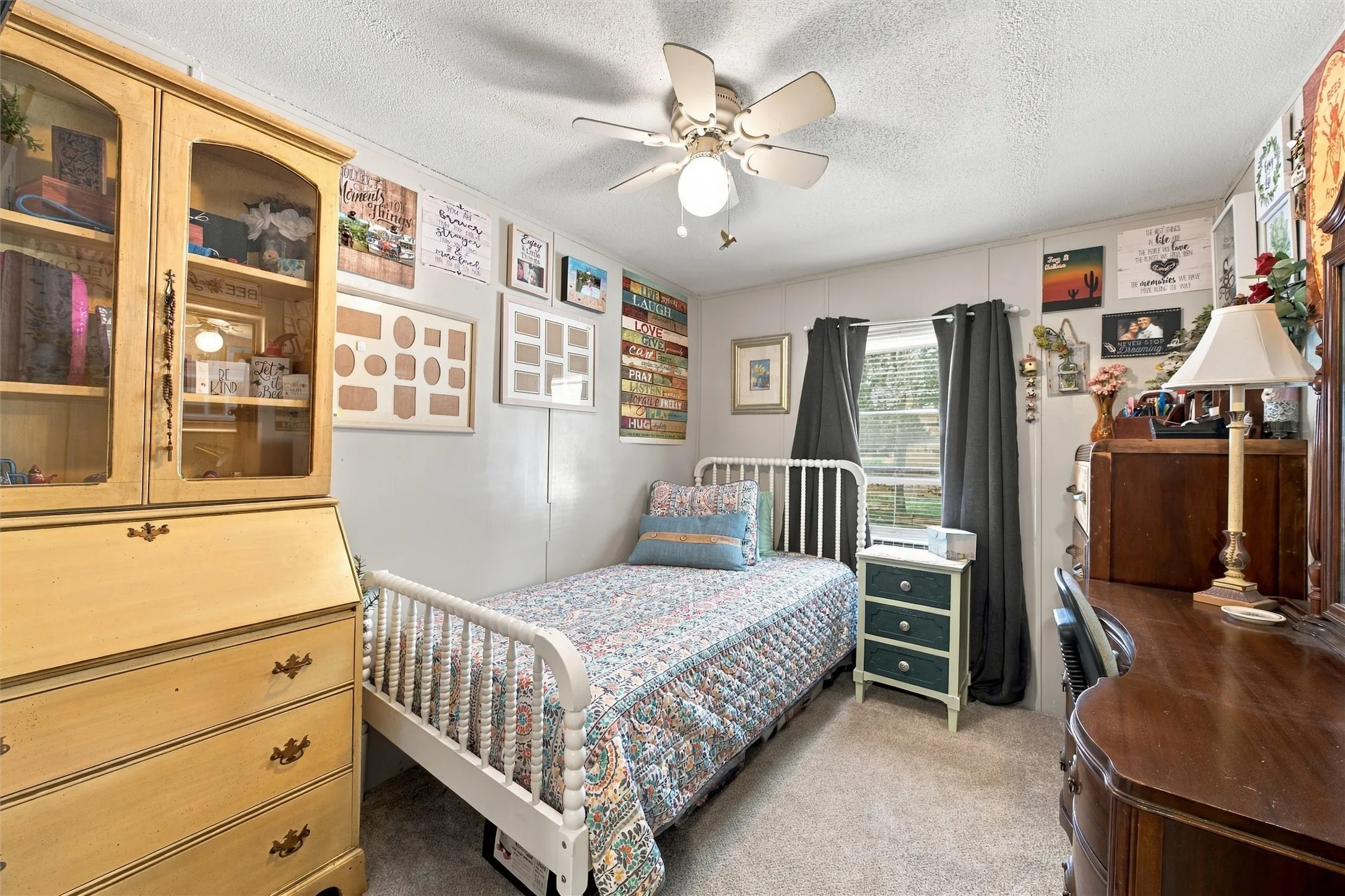 Carpeted room featuring a ceiling fan, a window with dark curtains, and light-colored walls