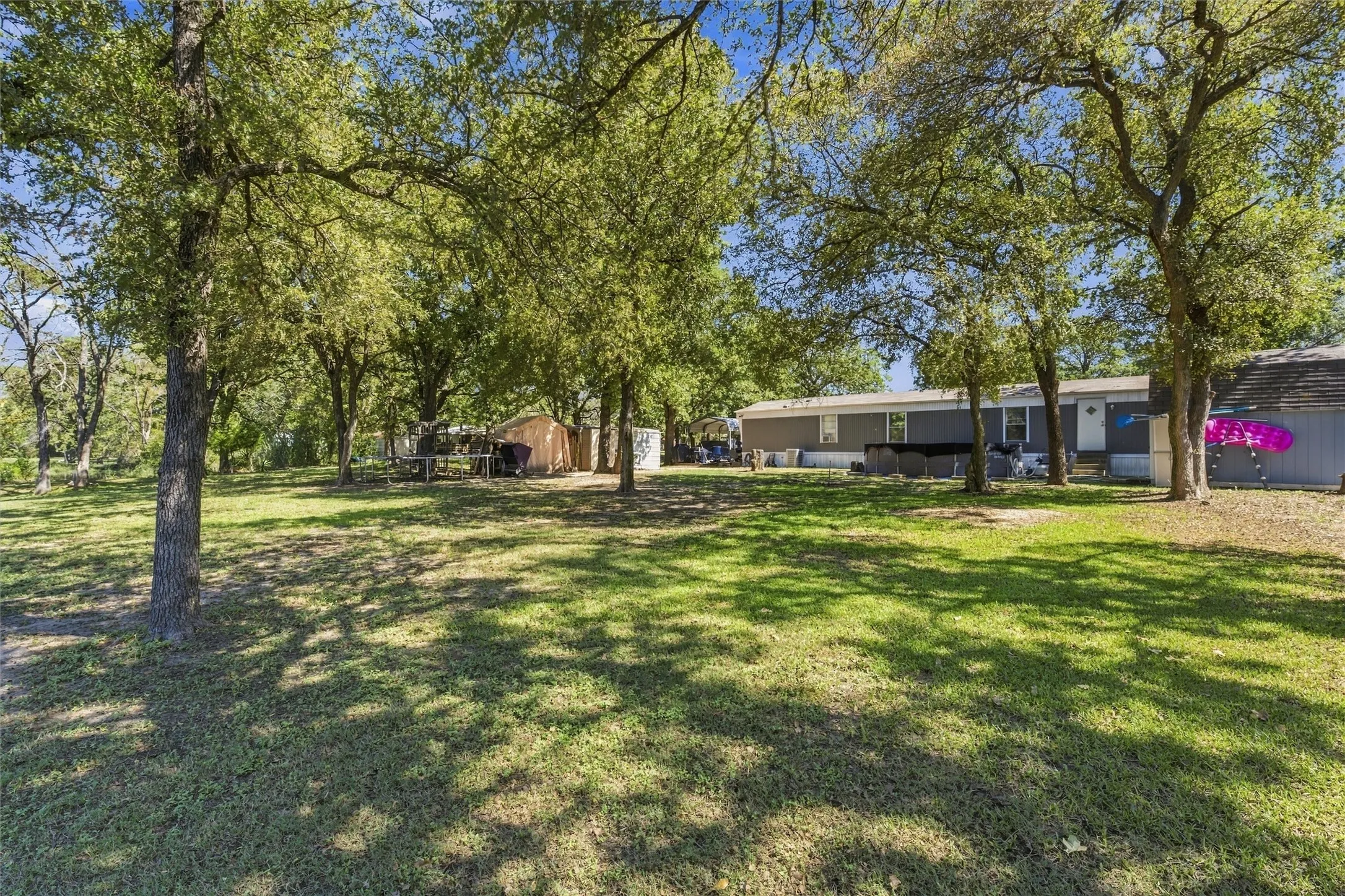Expansive green lawn with mature trees and a detached structure