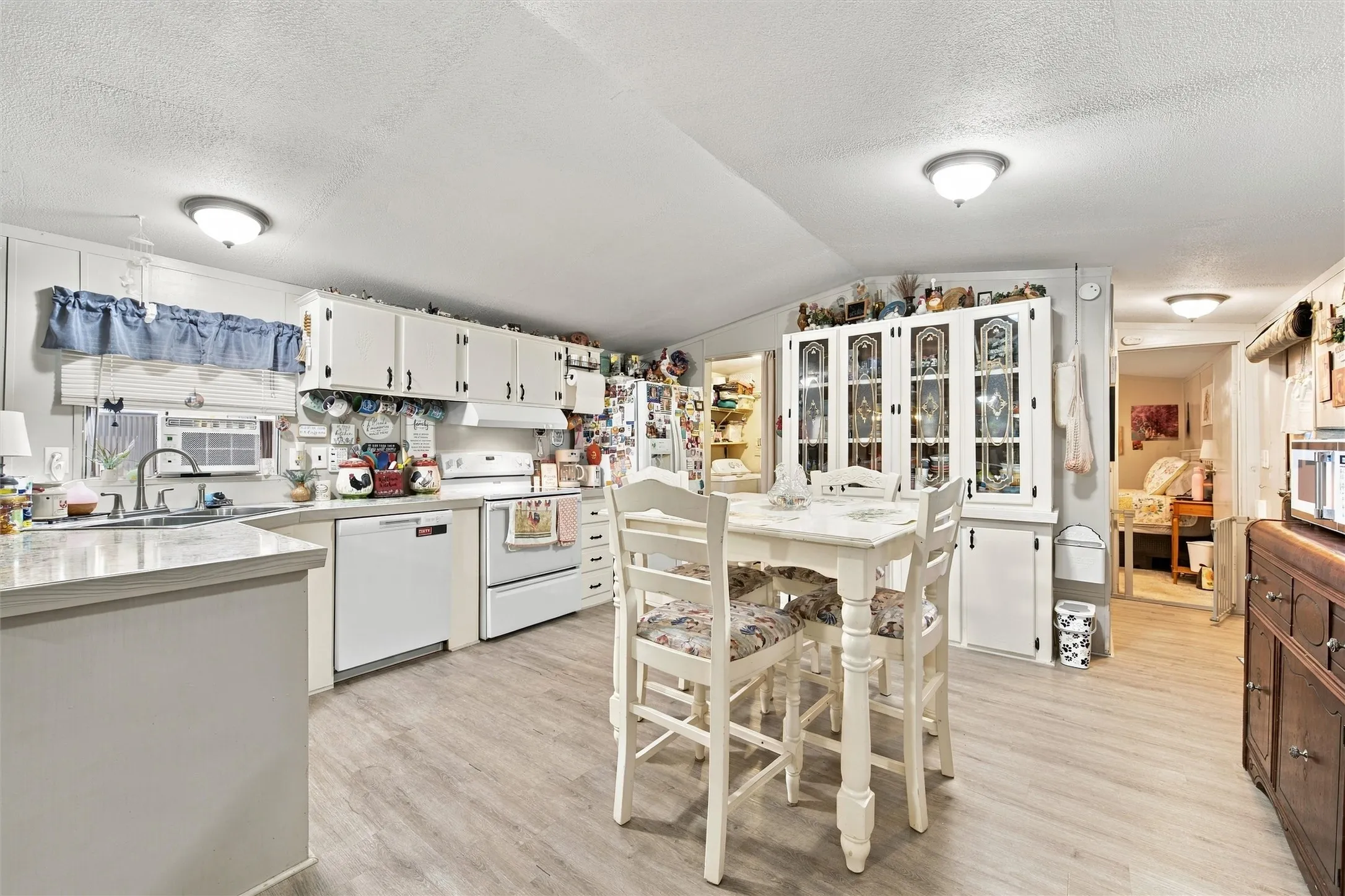 Kitchen featuring wood-finish flooring, white cabinetry, and a built-in display cabinet