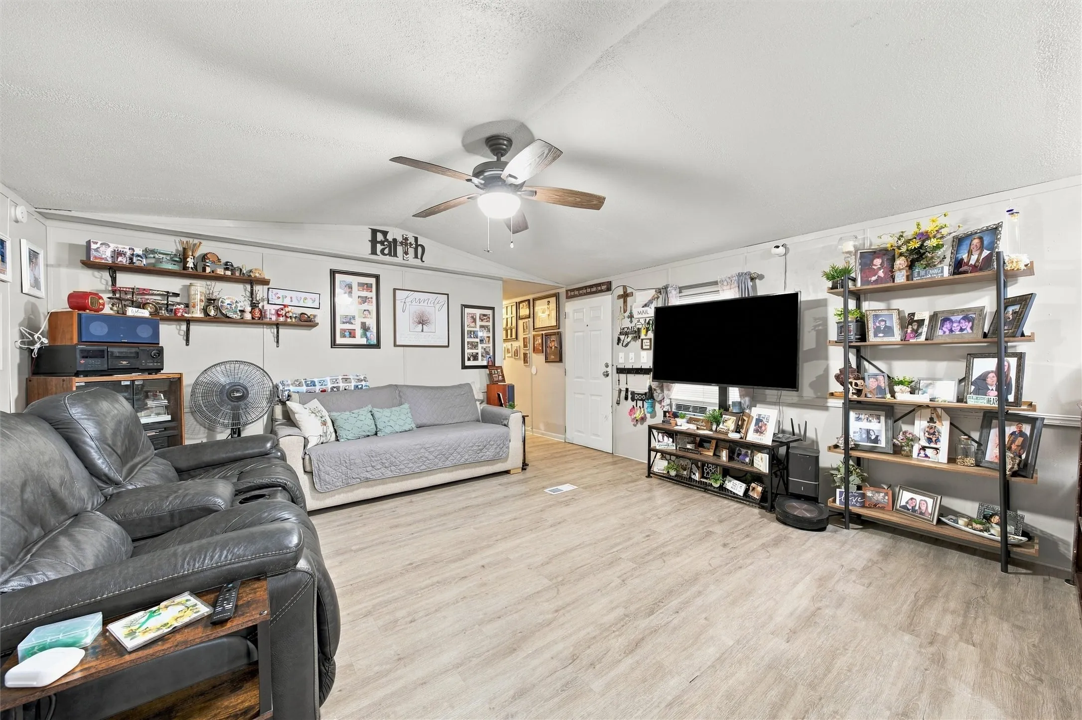 Wood-finish flooring throughout, ceiling fan with light fixture, and white painted walls