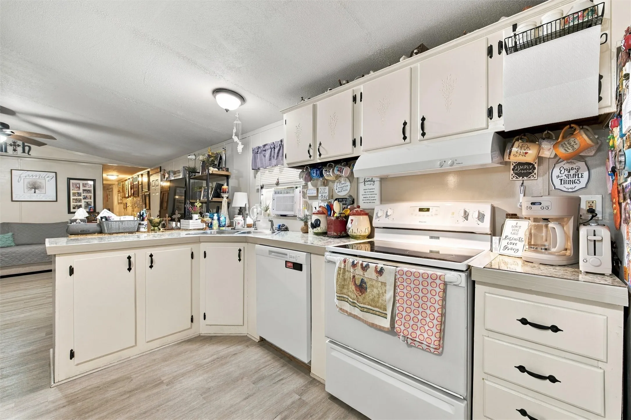 Kitchen featuring white cabinetry, light-toned countertops, a white electric range, and wood-finish flooring